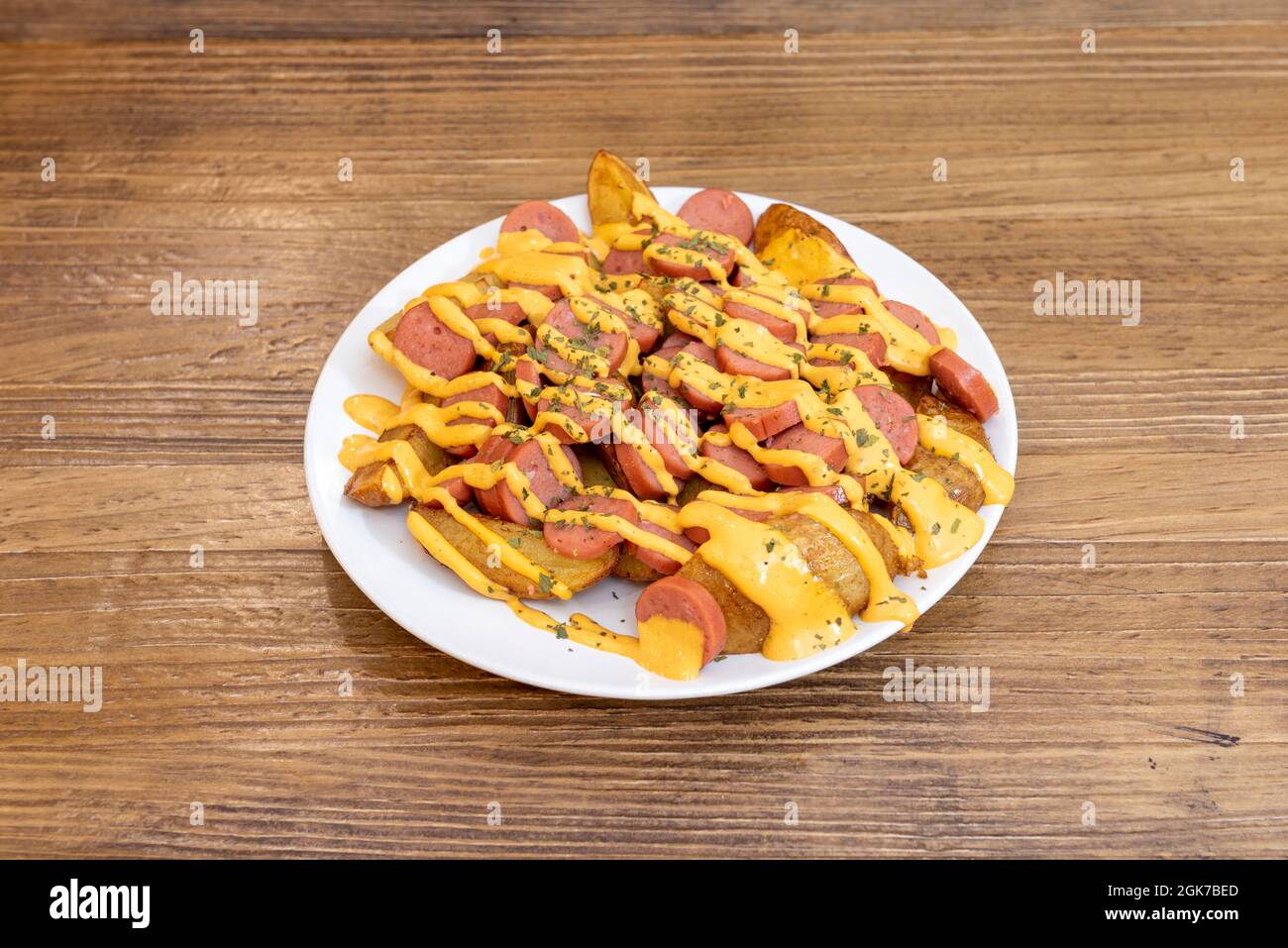 Ration de patatas bravas avec des saucisses frites en tranches et beaucoup de sauce épicée sur le dessus Banque D'Images