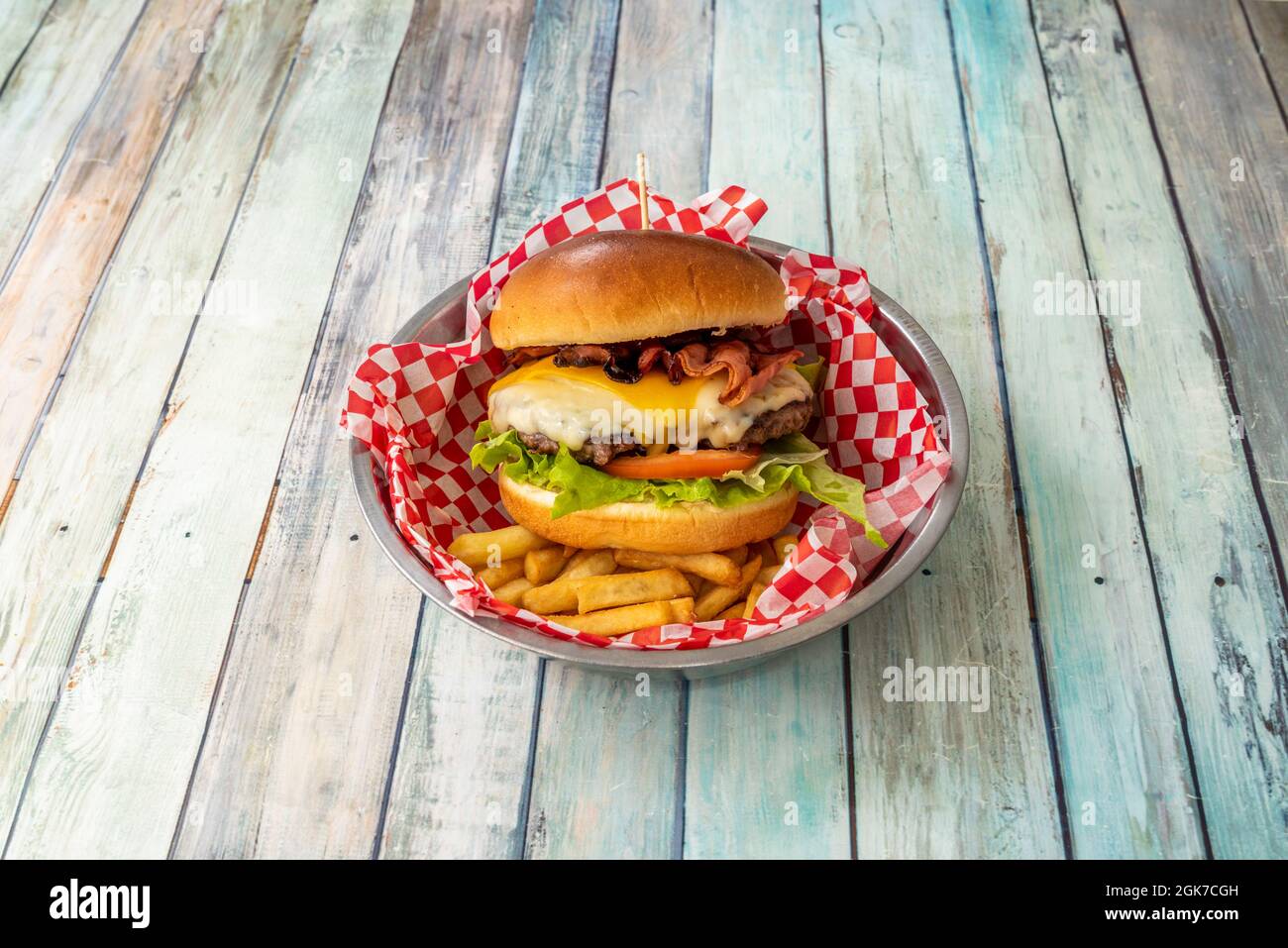 Cheeseburger amant avec beaucoup de fromage, bacon frit, laitue et tomate et bœuf sur un lit de frites Banque D'Images