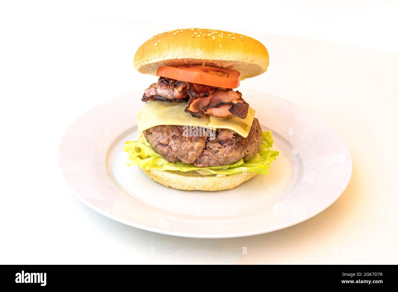 Hamburger avec un grand morceau de veau tranché, bacon gras frit et tranches de tomate avec laitue Banque D'Images