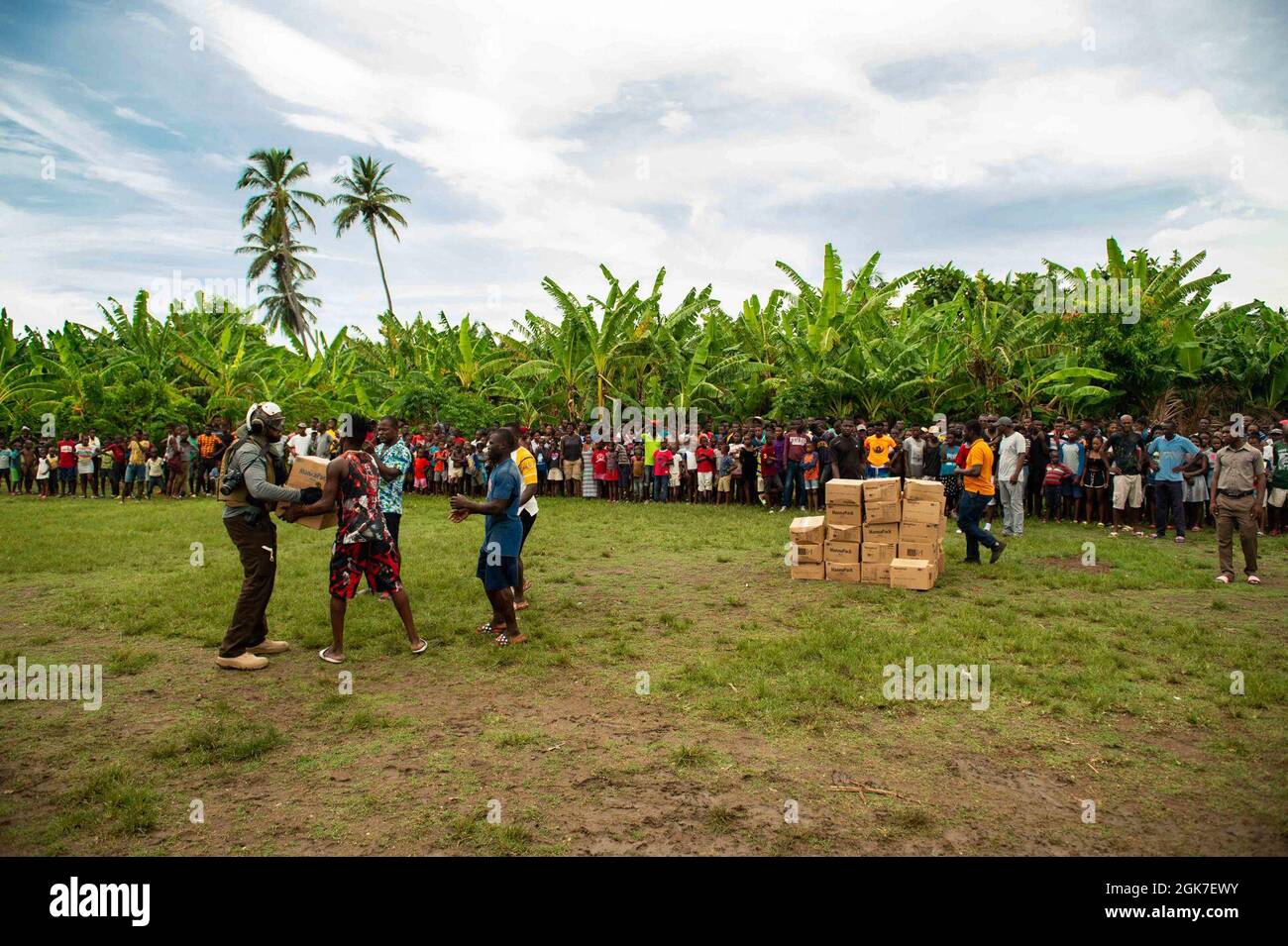 210825-N-MD802-1068 LACOHUANE, Haïti - (août 25, 2021) — les citoyens haïtiens reçoivent des boîtes de nourriture d'un agent du Service d'enquête criminelle de la marine (NCIS) livré par les « Chargers » de l'Escadron de combat de la mer des hélicoptères (HSC) 26, au cours d'une mission humanitaire et de secours en cas de catastrophe qui soutient l'Agence des États-Unis pour le développement international Banque D'Images