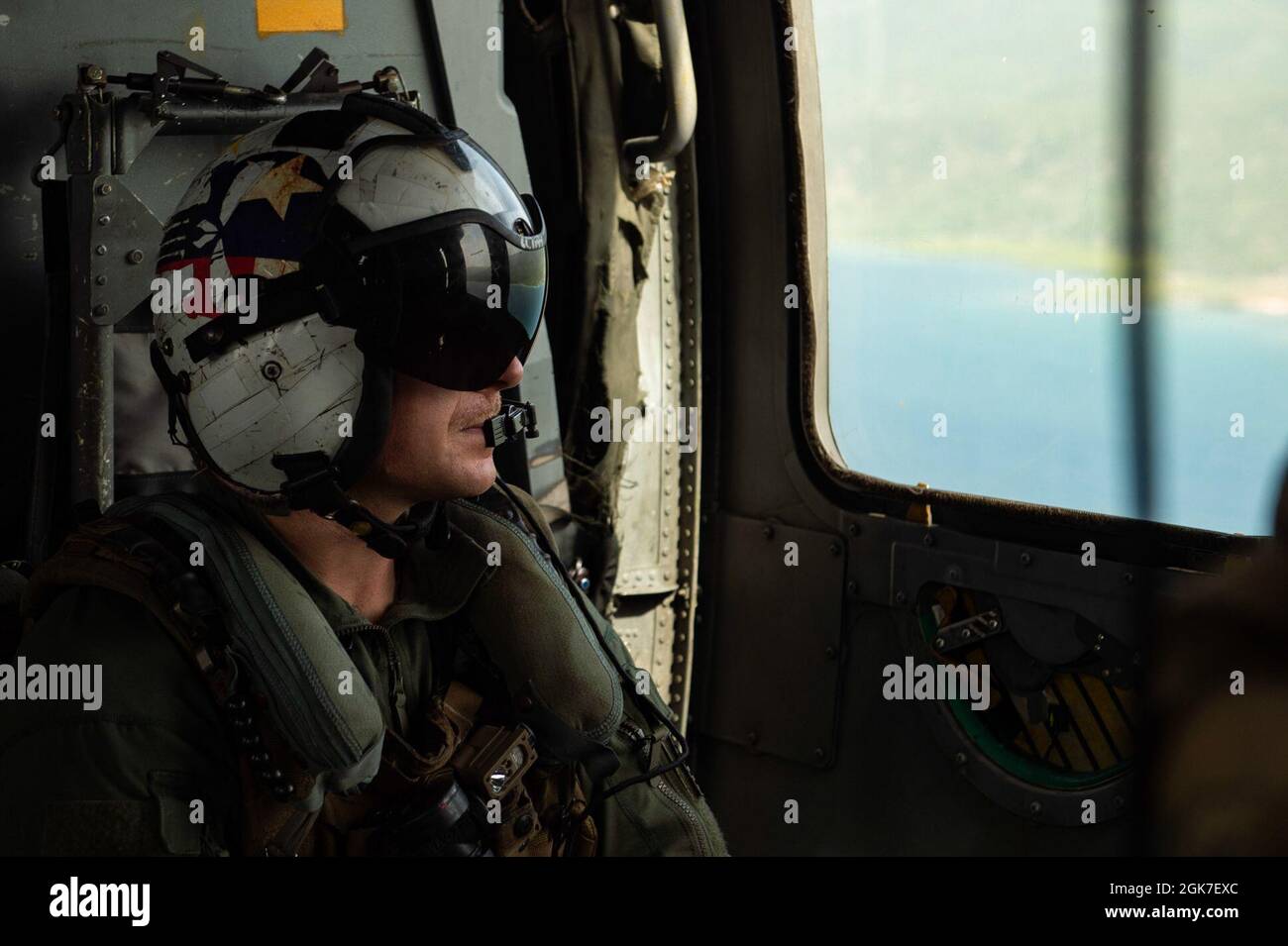 210825-N-MD802-1817 MER DES CARAÏBES - (AOÛT 25, 2021) — Cody Christian de 1re classe de l'Aircrewman (hélicoptère) de la marine, affecté aux “Chargers” de l'Escadron de combat de la mer d'hélicoptère (HSC) 26, regarde le rivage haïtien lors d'une mission d'aide humanitaire qui soutient l'Agence américaine pour le développement international Banque D'Images