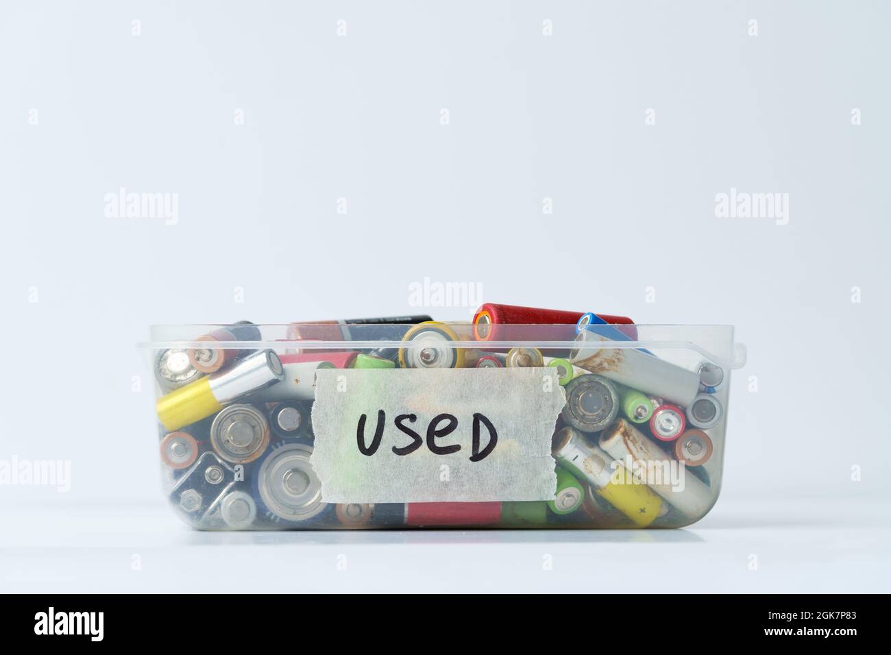 Gros plan de la batterie usagée dans un récipient en plastique sur le mur blanc. Concept de déchets dangereux électroniques. Banque D'Images