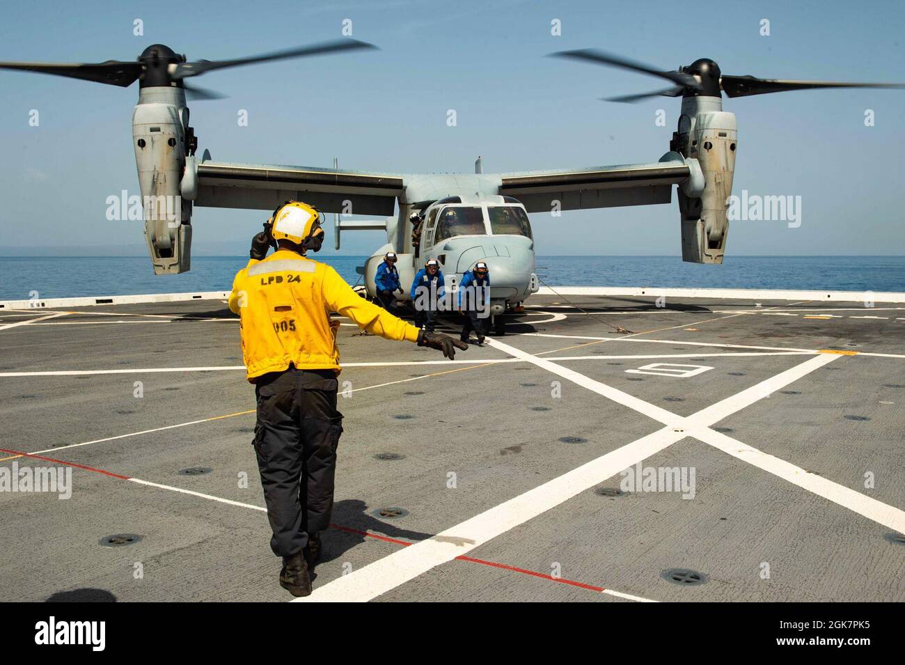 210828-N-MD802-1249 MER DES CARAÏBES - (AOÛT 28, 2021) — Aviation Boatswain’s Mate (Handling) 3rd Class Leandre Clements, stands atterrissage signaleur enlisé à bord du navire de transport amphibie de classe San Antonio USS Arlington (LPD 24) comme marins et un retour Marine de placer des cales et des chaînes sur un MV-22 Osprey, Affecté aux « Griffins de combat » de l’escadron de Tiltrotor moyen marin (VMM) 266, le 28 août 2021. Arlington est déployé au Commandement Sud des forces navales américaines/États-Unis 4e flotte pour soutenir les efforts d'aide humanitaire et de secours en cas de catastrophe (HADR) en Haïti après une oreille de magnitude 7.2 Banque D'Images