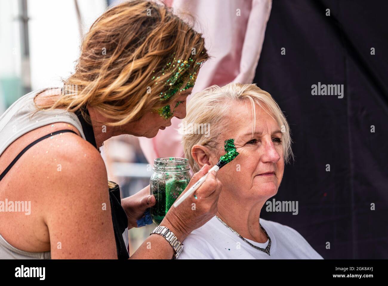 Peinture de visage lors d'un festival de concert de musique à Garon Park, Southend on Sea, Essex, Royaume-Uni. Femme âgée, adulte senior, à motif de peinture pailletée Banque D'Images