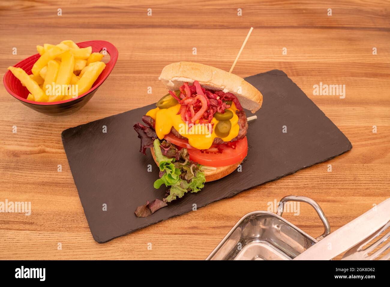 délicieux hamburger de bœuf au fromage cheddar, tranches de bacon frites, tomates en tranches, tranches de jalapeño et laitue en chêne Banque D'Images délicieux hamburger de bœuf au fromage cheddar, tranches de bacon frites, tomates en tranches, tranches de jalapeño et laitue en chêne Banque D'Images