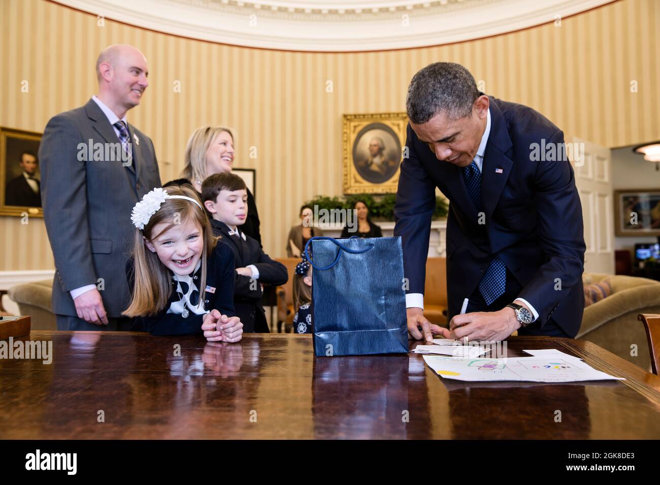 Le président Barack Obama signe des souvenirs pour le mois de mars des dix 2013 l'ambassadrice nationale Nina Centofanti, 8 ans, au bureau de Resolute lors de sa visite au bureau ovale, le 26 mars 2013. Les parents de Centofanti Vince et Christine, le frère Nicholas, et la sœur Mia, non visibles, se tiennent derrière elle. (Photo officielle de la Maison Blanche par Pete Souza) cette photo officielle de la Maison Blanche est disponible uniquement pour publication par les organismes de presse et/ou pour impression personnelle par le(s) sujet(s) de la photo. La photographie ne peut être manipulée d'aucune manière et ne peut pas être utilisée dans des m commerciaux ou politiques Banque D'Images