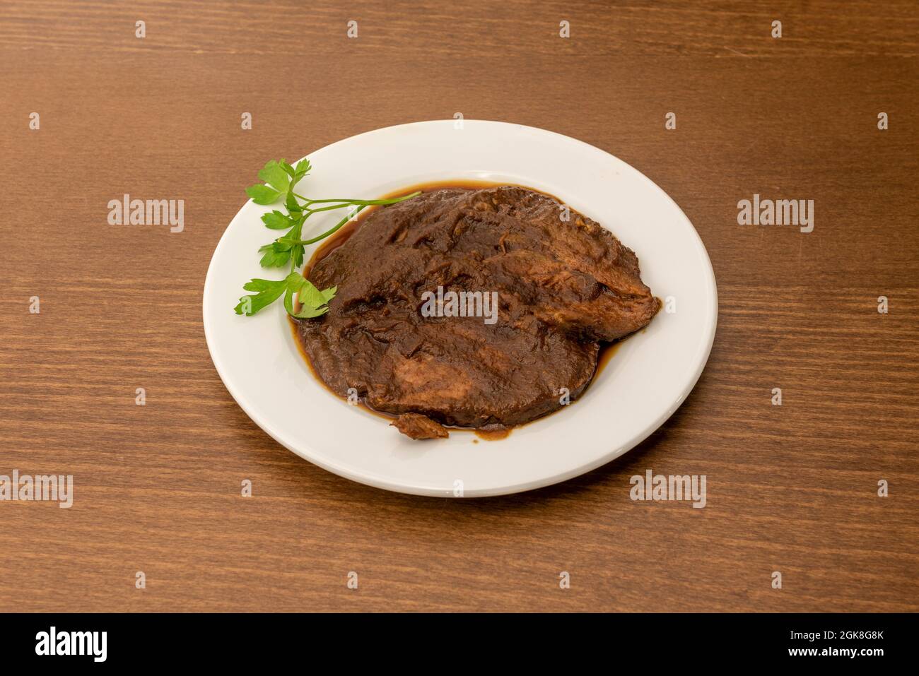 Recette espagnole de joue de boeuf compotée avec du persil servi sur une assiette blanche Banque D'Images