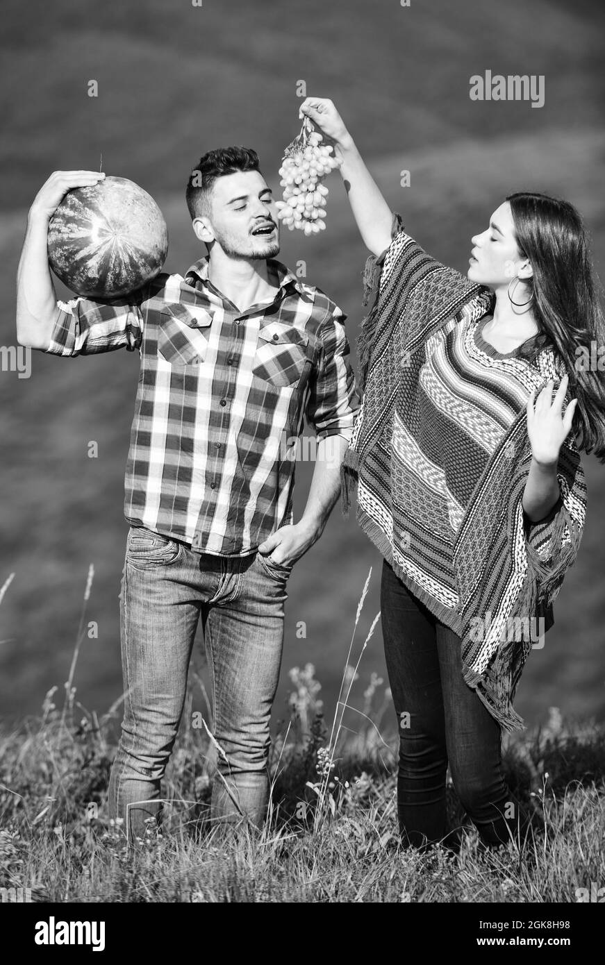 bio et sain. hippie couple avec fruits. vitamine et diète. nourriture d'été. homme et femme tiennent le melon d'eau. fille et garçon mangent le raisin. été Banque D'Images