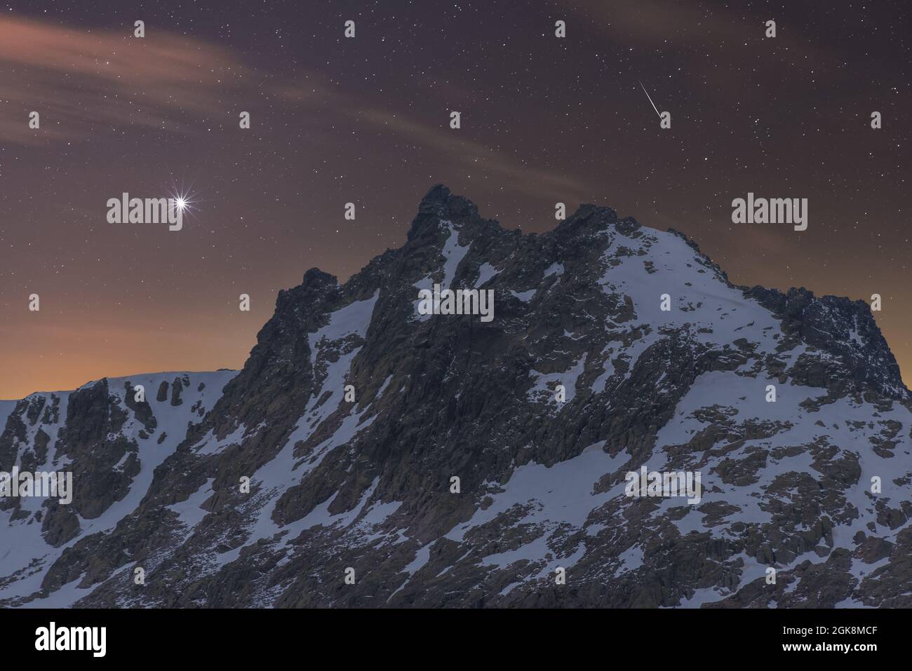 Vue panoramique sur les montagnes sombres avec neige et pics accidentés sous le ciel étoilé au crépuscule Banque D'Images