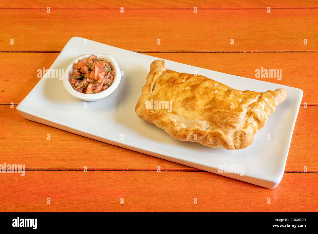 Empanada créole chilienne avec accompagnement d'oignon violet et de persil sur une assiette blanche Banque D'Images