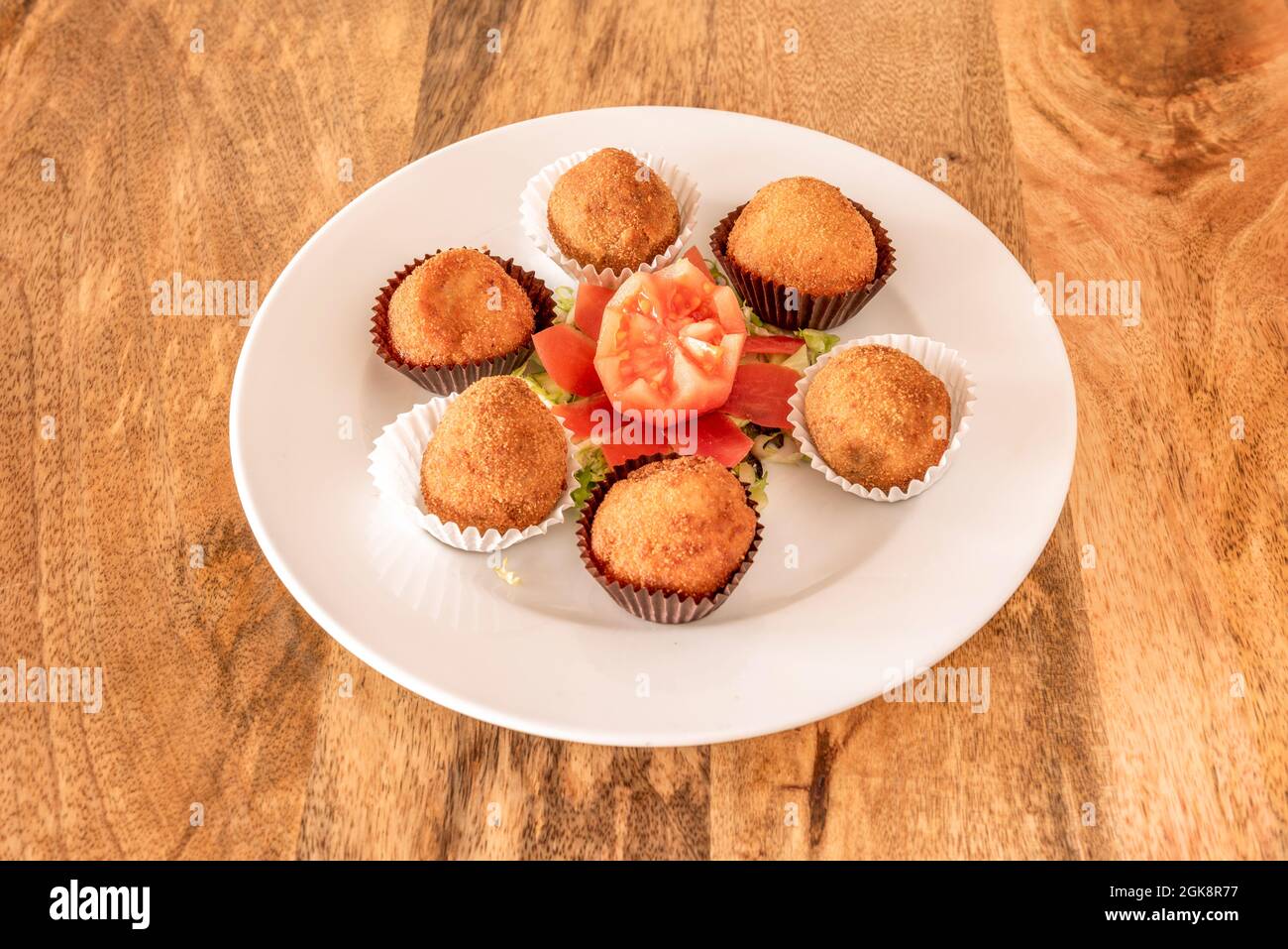 Croquettes fines de jambon jerky et ibérique accompagnées d'une fleur de tomate servies sous forme de chocolats sur une assiette blanche Banque D'Images