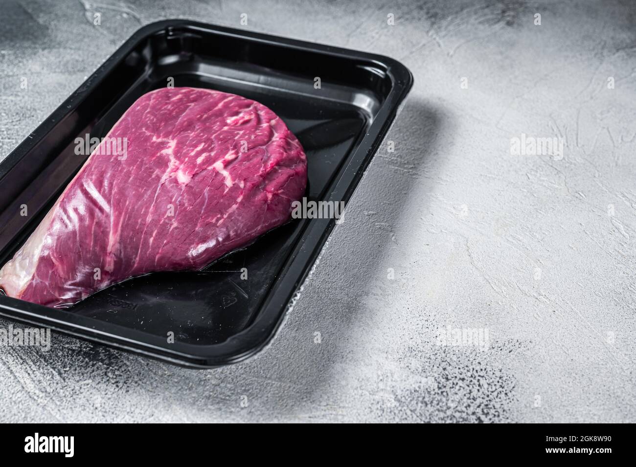 Steak de bœuf cru ou steak de viande de bœuf au sirloin dans un emballage sous vide. Arrière-plan blanc. Vue de dessus. Copier l'espace Banque D'Images