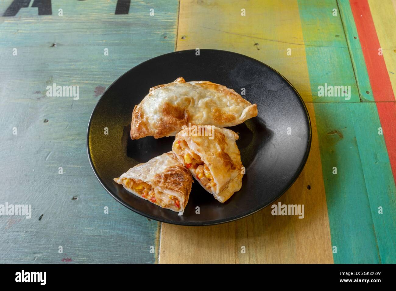 Pâte feuilletée Argentine empanadas la première partie en moitié pour voir l'intérieur sur une assiette noire Banque D'Images