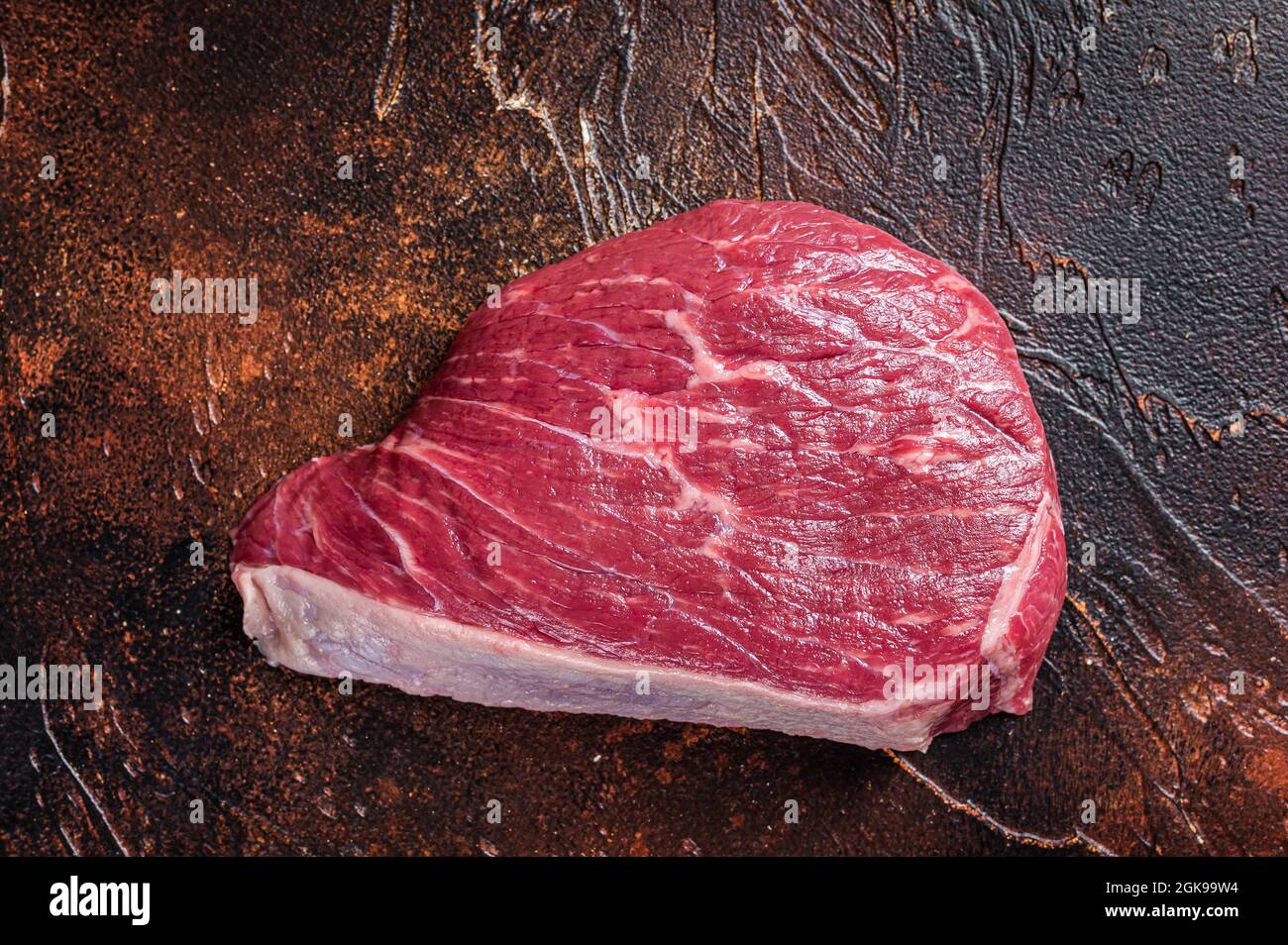 Bœuf cru coupé ou steak de viande de sirloin sur la table de boucher. Arrière-plan sombre. Vue de dessus Banque D'Images