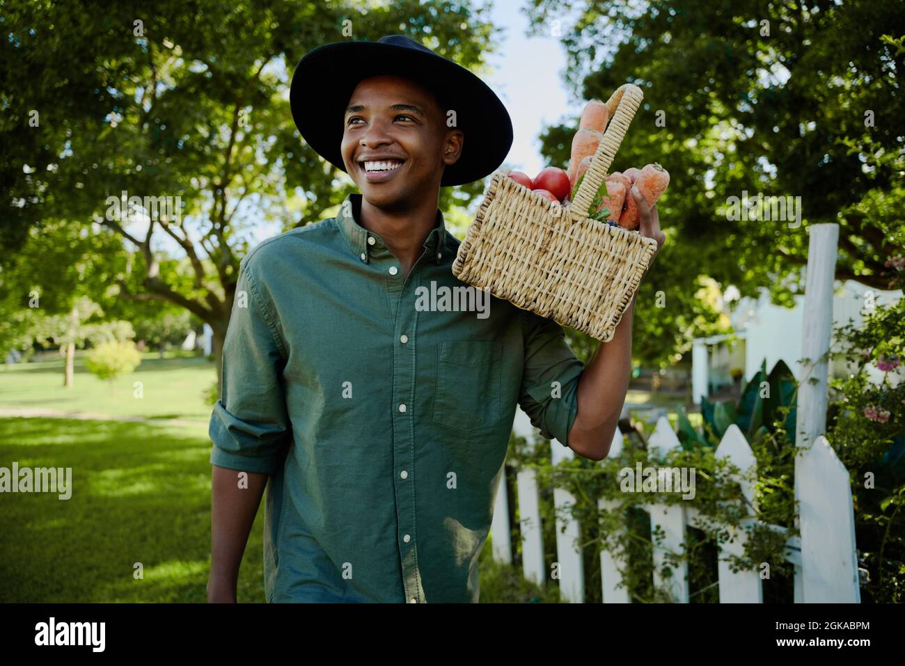 Race mixte fermier mâle marchant à l'extérieur tenant le panier de légumes Banque D'Images