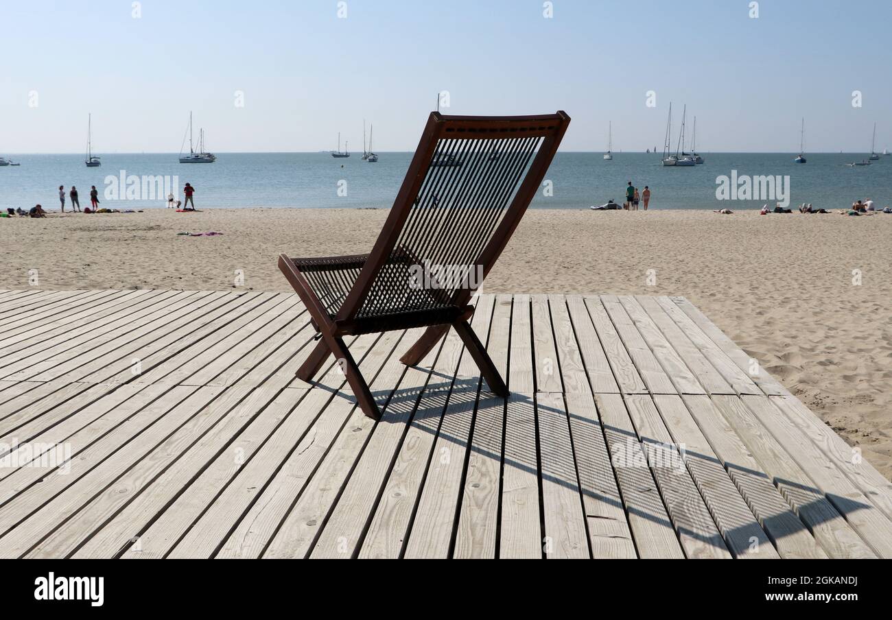 Chaise sur le pont au lac de la plage Markermeer avec des voiliers sur l'eau sous le ciel bleu, Marker Wadden, pays-Bas, septembre 2021 Banque D'Images