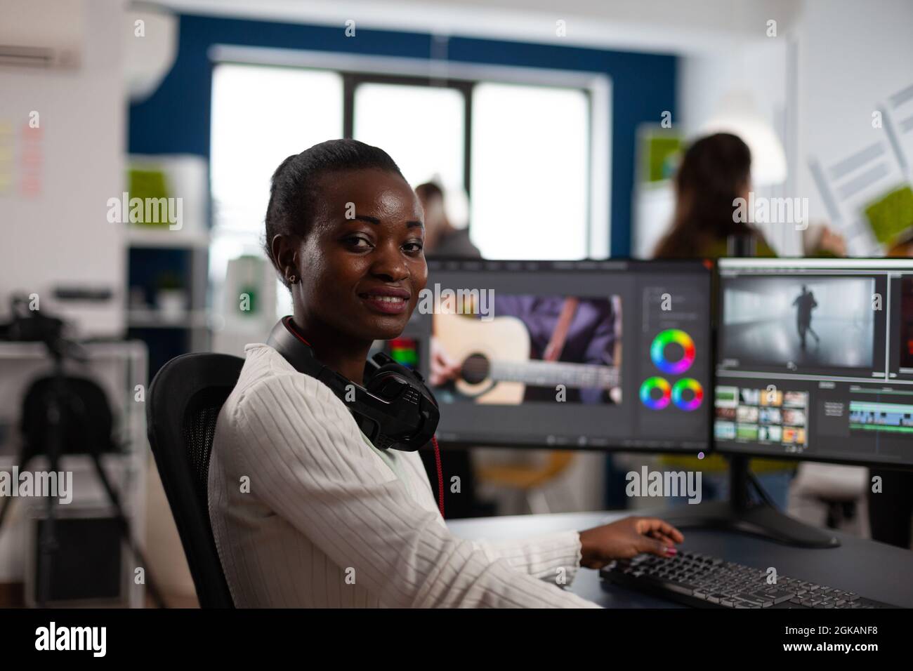 Éditeur de vidéo afro-américain artiste regardant la caméra souriant montage vidéo projet créatif dans le logiciel de post-production travaillant dans startup studio bureau. Montage de films audio par un vidéaste Banque D'Images