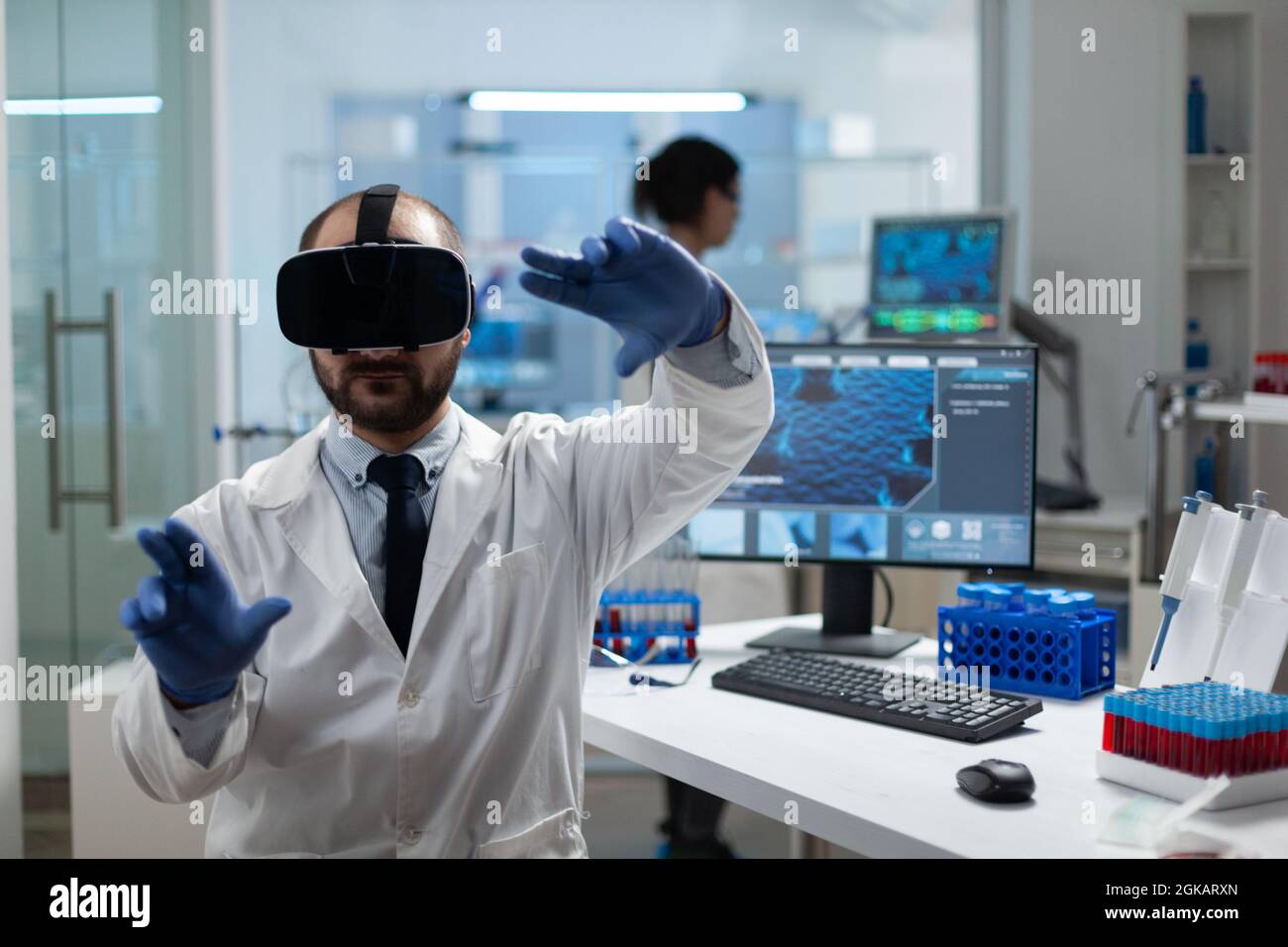 Chimiste chercheur analysant le développement de la maladie à l'aide d'un casque de réalité virtuelle pendant une expérience médicale en laboratoire hospitalier de biochimie. Équipement de biotechnologie moderne Banque D'Images