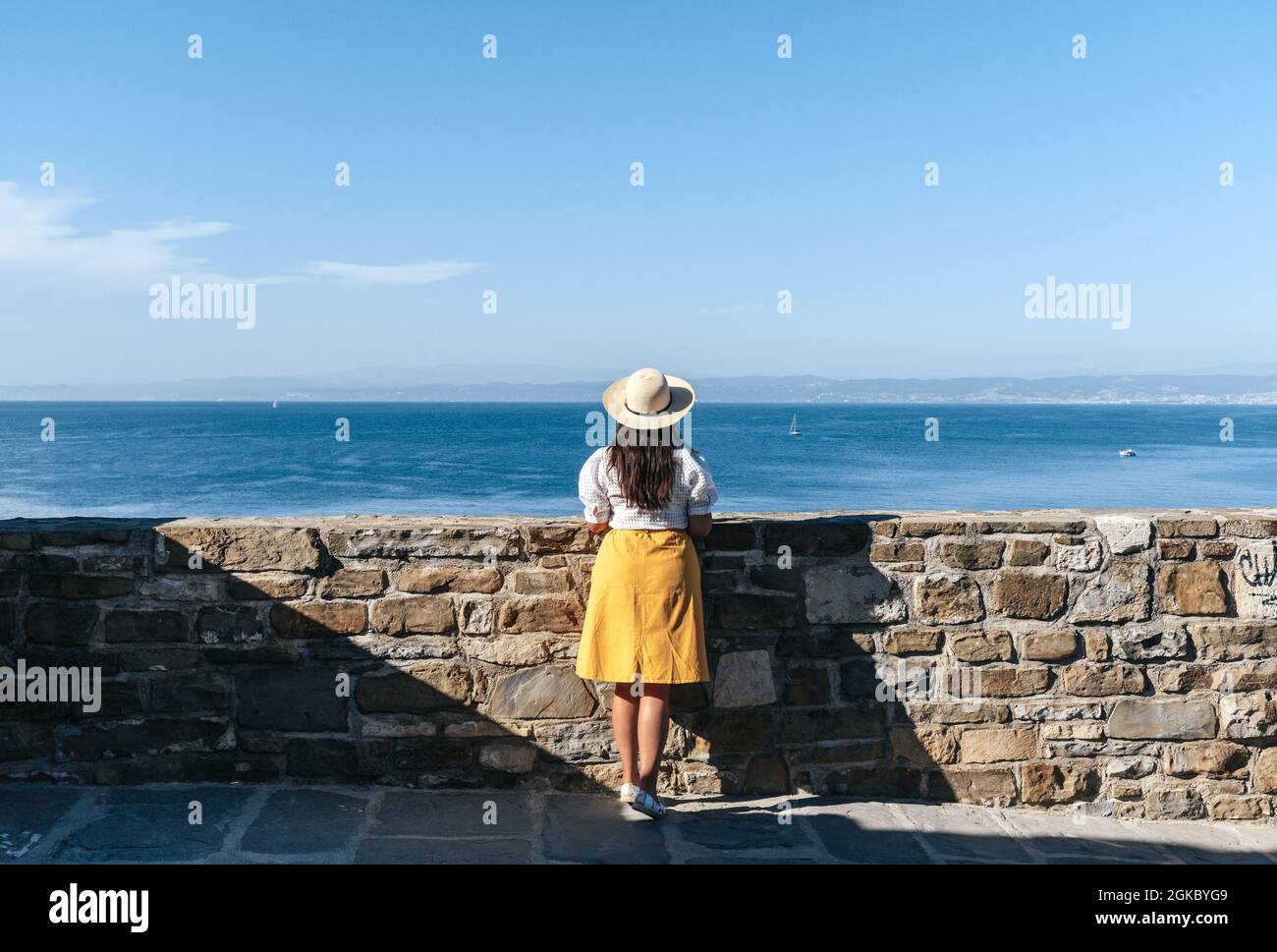 Vue arrière d'une jeune femme élégante se tenant sur le point de vue de la mer à Piran, en Slovénie. Banque D'Images