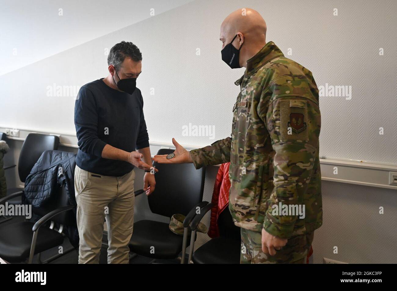 Sascha Lingauer, représentante de l'officier contractuel du 786e Escadron du génie civil, accepte une pièce de la U.S. Air Force Brig. Le général Josh Olson, 86e commandant de l'escadre du transport aérien, lors d'une cérémonie de reconnaissance à la base aérienne de Ramstein, en Allemagne, le 9 mars 2021. Lindauer a permis la désinfection de 89 installations dans la communauté militaire de Kaiserslautern. Banque D'Images