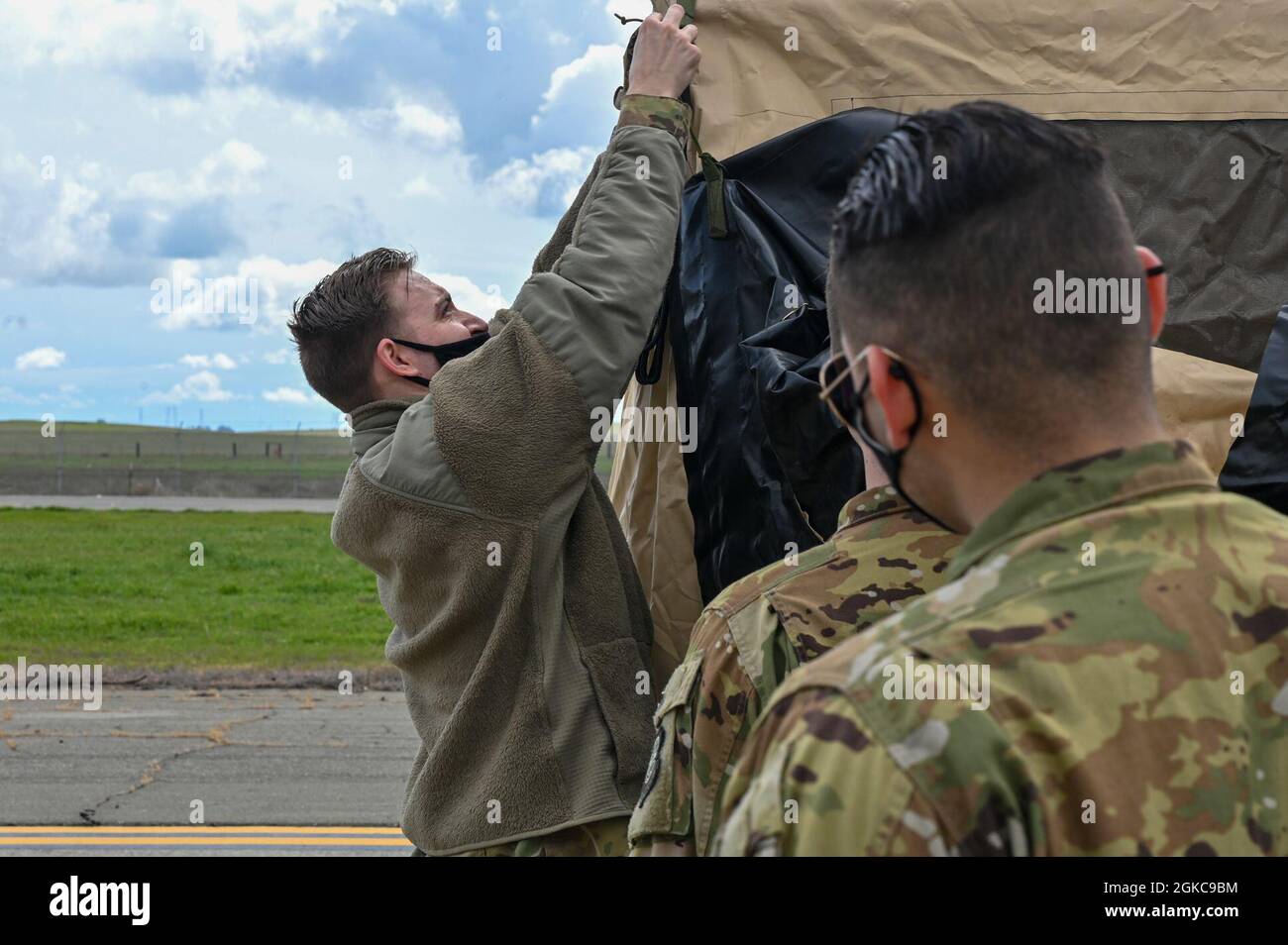 Un Airman du 821e Escadron d'intervention en cas d'urgence de la base aérienne de Travis, en Californie, forme des aviateurs de la base aérienne de Little Rock, en Arkansas, sur la façon d'installer une tente à la base aérienne de Travis, le 10 mars 2021. Les aviateurs du 61e Escadron de transport aérien ont reçu une formation avec le 821e CRS pour présenter le concept des aviateurs multi-capacités en les formant à exécuter des tâches en dehors de leur description de travail spécifique. Banque D'Images