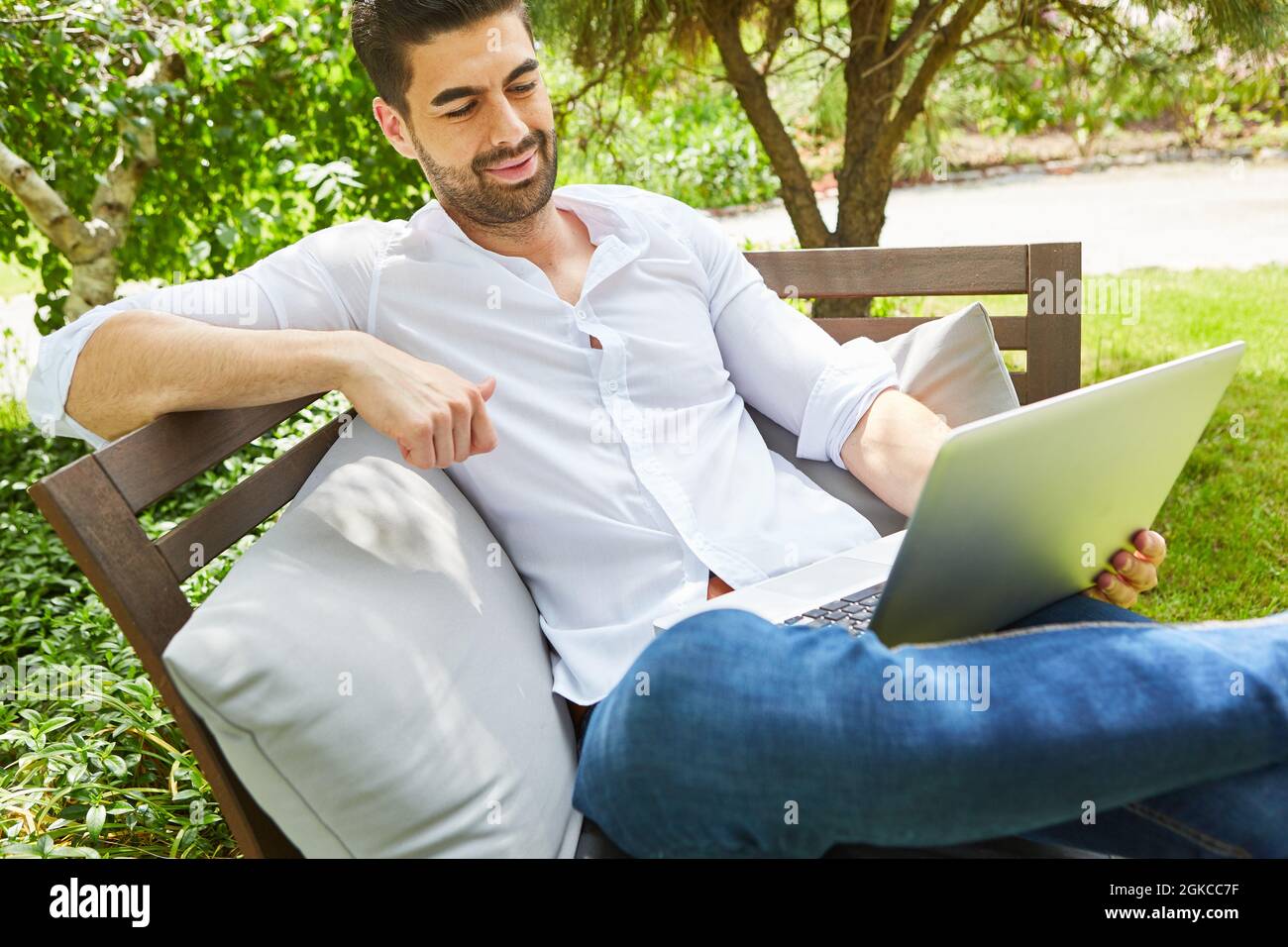 Influenceur ou freelance cool dans le jardin en été sur l'ordinateur portable en ligne Banque D'Images