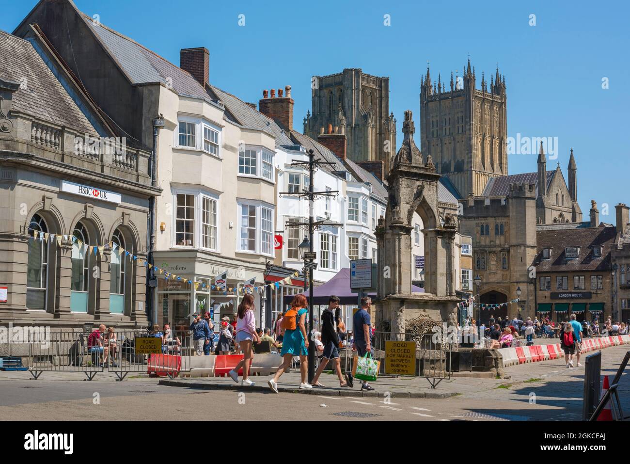 Wells Somerset, vue en été des personnes qui marchent le long de l'historique Market place Cross and Fountain dans le centre de Wells, Somerset, Angleterre, Royaume-Uni Banque D'Images