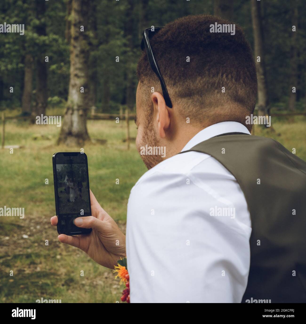 un homme de course mixte habillé avec élégance prenant une photo avec son téléphone portable ou portable Banque D'Images