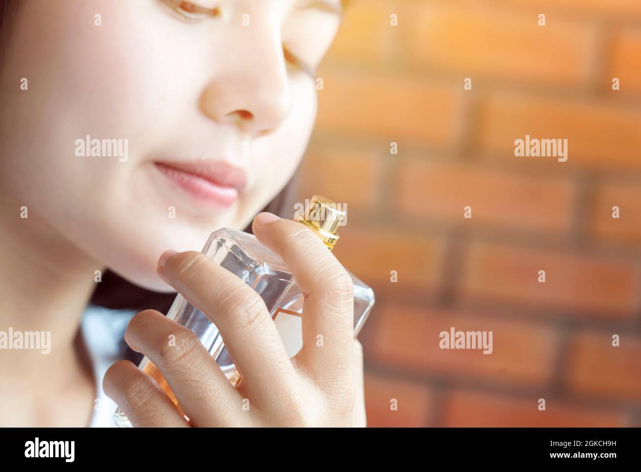 Jeune fille sentant son parfum. Jeune belle femme tenant une bouteille de parfum et d'odeur d'arôme. Rose doux. gros plan Banque D'Images