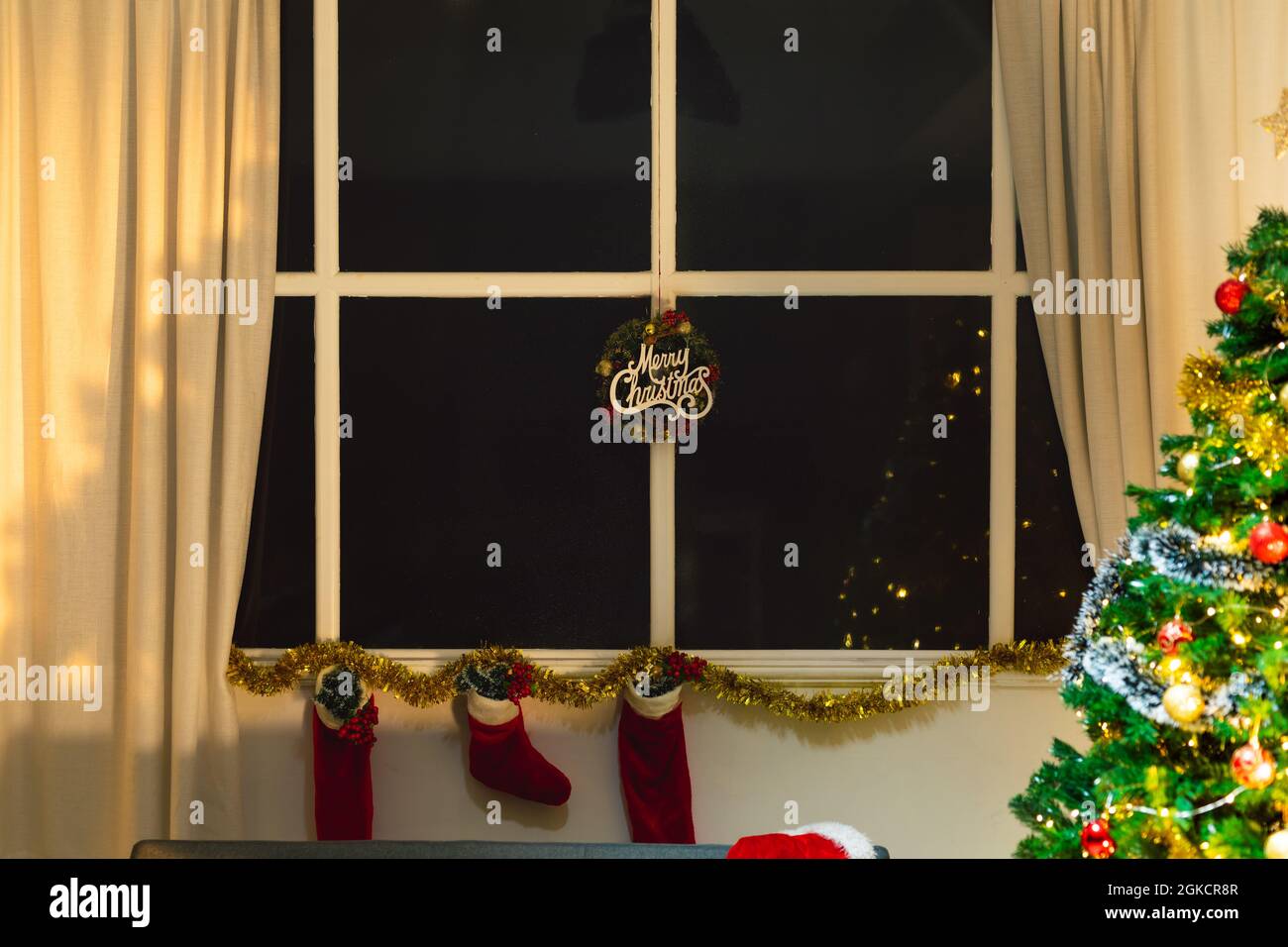 Composition de l'affiche de joyeux noël dans la fenêtre, avec des bas de noël et un sapin de noël Banque D'Images Composition de l'affiche de joyeux noël dans la fenêtre, avec des bas de noël et un sapin de noël Banque D'Images