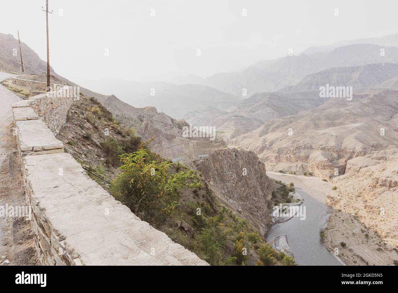 Couches de montagnes et collines rocheuses dans la brume matinale, coude d'une rivière dans un canyon, vue de dessus, de la route clôturée avec une clôture en pierre. Déplacement Banque D'Images