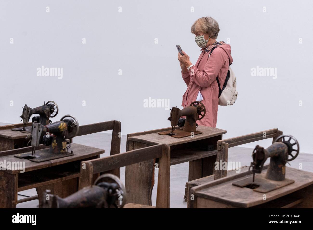 Londres, Royaume-Uni. 14 septembre 2021. Une femme voit Capital cadavres (2021) par Ibrahim Mahama, 100 machines à coudre en métal rouillé fixées aux bureaux d'école en bois. Aperçu de «Lazarus», la nouvelle exposition solo d’Ibrahim Mahama à la galerie White Cube de Bermondsey qui présente des installations à grande échelle, des sculptures et des collages. L'exposition est le résultat de plusieurs mois de recherche à Nkrumah Volini, dans le nord du Ghana, un silo en béton abandonné accueillant une grande colonie de chauves-souris qui a inspiré certains des travaux exposés. Le spectacle se déroulera du 15 septembre au 7 novembre 2021. Credit: Stephen Chung / Alamy Live News Banque D'Images Londres, Royaume-Uni. 14 septembre 2021. Une femme voit Capital cadavres (2021) par Ibrahim Mahama, 100 machines à coudre en métal rouillé fixées aux bureaux d'école en bois. Aperçu de «Lazarus», la nouvelle exposition solo d’Ibrahim Mahama à la galerie White Cube de Bermondsey qui présente des installations à grande échelle, des sculptures et des collages. L'exposition est le résultat de plusieurs mois de recherche à Nkrumah Volini, dans le nord du Ghana, un silo en béton abandonné accueillant une grande colonie de chauves-souris qui a inspiré certains des travaux exposés. Le spectacle se déroulera du 15 septembre au 7 novembre 2021. Credit: Stephen Chung / Alamy Live News Banque D'Images