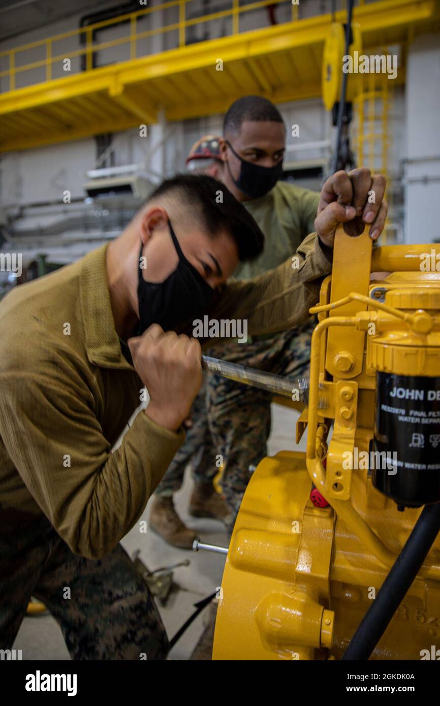 CPL marine des États-Unis Edgar Martinez, à gauche, un technicien en réfrigération et climatisation, et Cpl. Ja’kove McCullum, soudeur de transport de moteur à combat Logistics Company (CLC) 36, attache les pièces d’un ancien moteur pour le tracteur John Deere, à bandage en caoutchouc, direction articulée, multi-usages (TRAM) à bord de la station aérienne Marine corps Iwakuni, Japon, le 22 mars 2021. Le CLC-36 abrite les services de disposition de l’Agence de logistique de la défense (DLA) de la station aérienne, anciennement connus sous le nom de Bureau de réutilisation et de commercialisation de la défense ou CRMO, où les unités à bord du MCAS Iwakuni prennent des articles et du matériel qu’elles ne prennent pas longtemps Banque D'Images