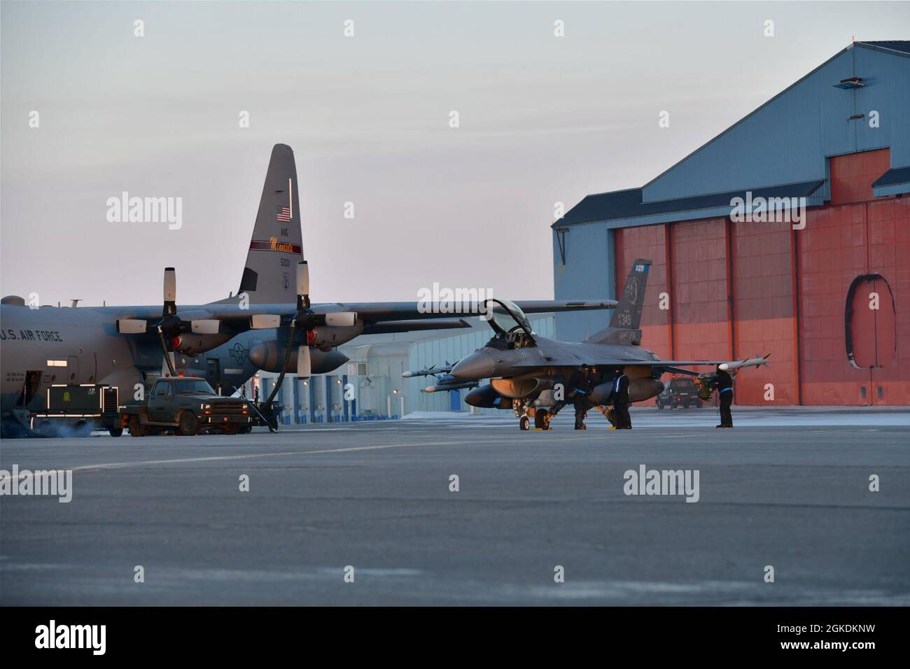 Le personnel d’entretien des aéronefs de la Garde nationale aérienne du Minnesota de la 148e Escadre de chasseurs et de la 133e Escadre de transport aérien travaille côte à côte sur les F’16 et un C-130 à la base aérienne de Thule, au Groenland, lors de l’exercice de défense aérienne arctique du Commandement de l’aérospatiale de l’Amérique du Nord, Aralgam Dart 21-02, le 23 mars 2021. L'exercice se tiendra à partir de mars 20-26 et s'étendra de la mer de Beaufort à Thule, au Groenland, et s'étendra vers le sud, le long de l'Atlantique est, jusqu'à la côte américaine du Maine. Amalgame Dart 21-2 offre au NORAD l'occasion de perfectionner ses compétences en matière de défense du territoire à mesure que les forces canadiennes, américaines et de l'OTAN opèrent ensemble dans le cadre de l'ARCT Banque D'Images