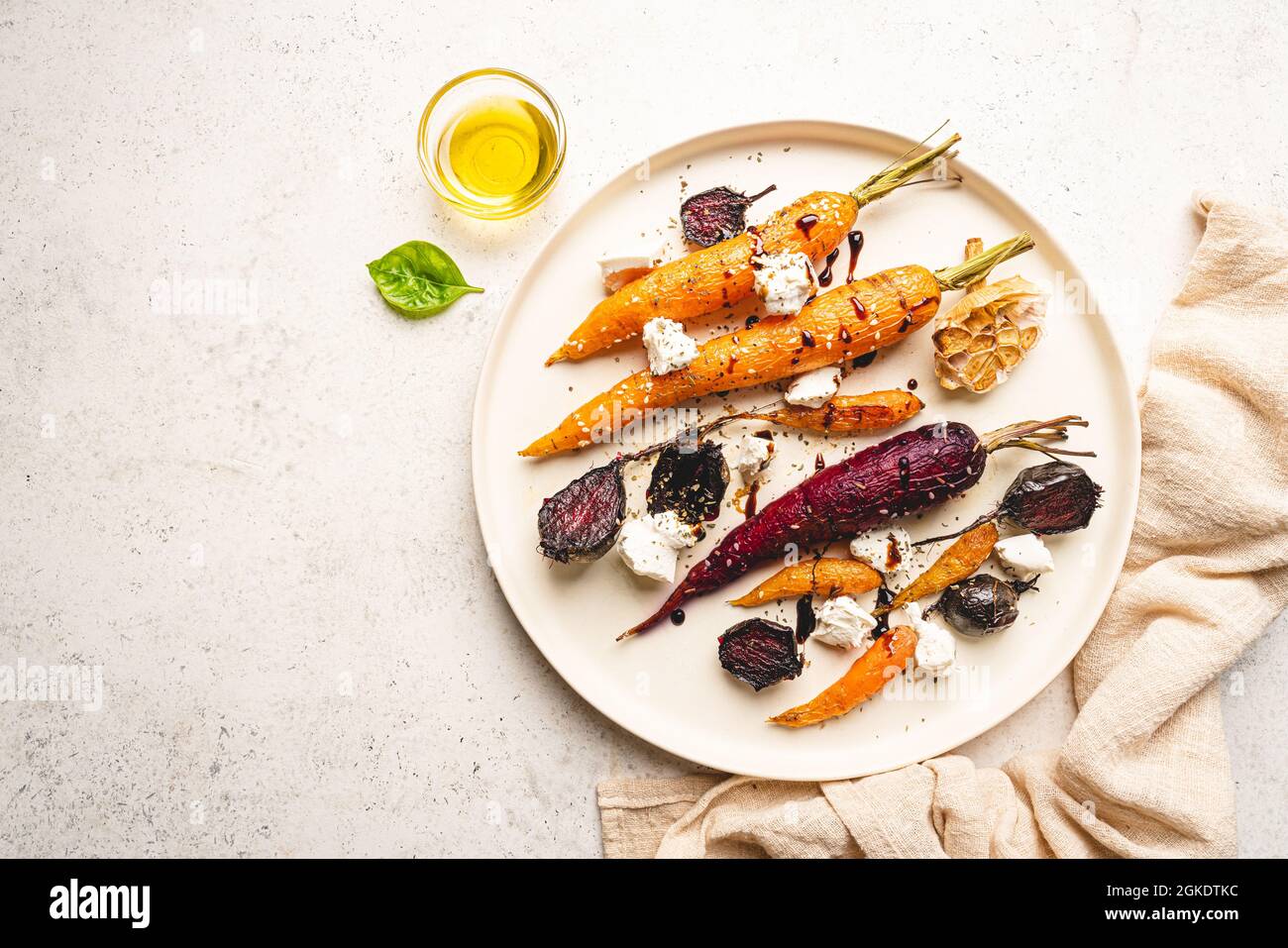 Jeunes carottes entières et colorées rôties aux herbes et au fromage servis sur une assiette sur fond blanc. Vue de dessus Banque D'Images