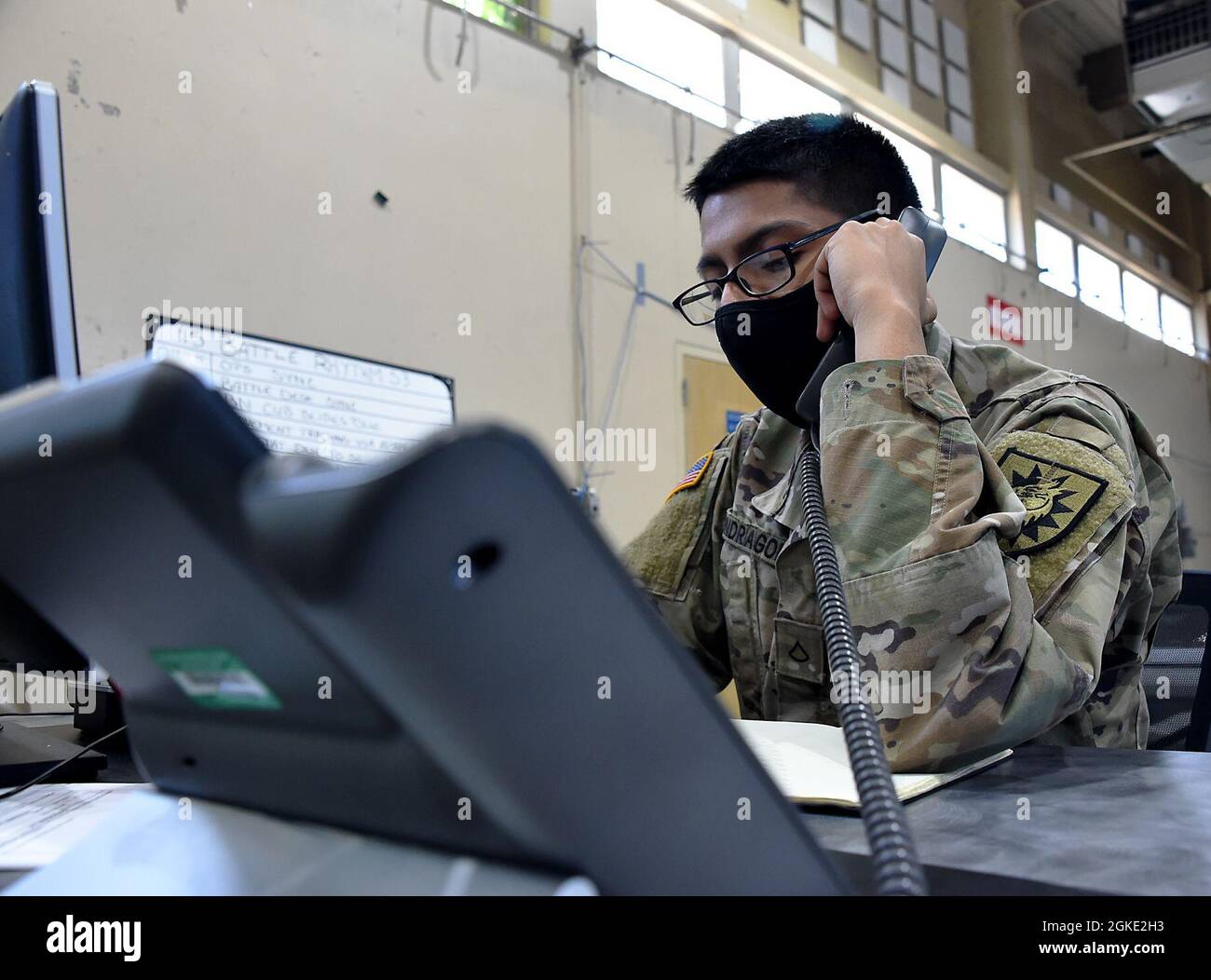 PFC de l'armée américaine. Jonathan Mondragon, mécanicien de véhicules à roues du 749e Bataillon de soutien au combat de la Garde nationale de Californie, répond au téléphone au bureau de bataille de la section des opérations, Benicia, Californie, le 25 mars 2021. Mondragon est actuellement en mission avec la Force opérationnelle interarmées 749 où il travaille comme opérateur APAN du matin dans la section des opérations. Banque D'Images