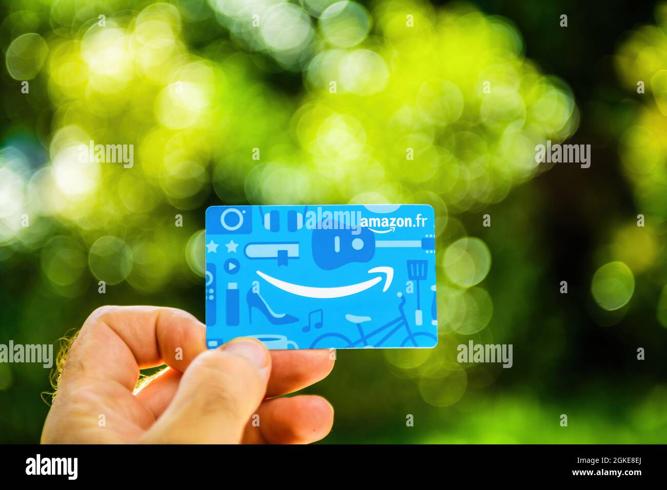 POV main mâle tenant nouveau Amazon France fr carte cadeau contre parc vert Banque D'Images