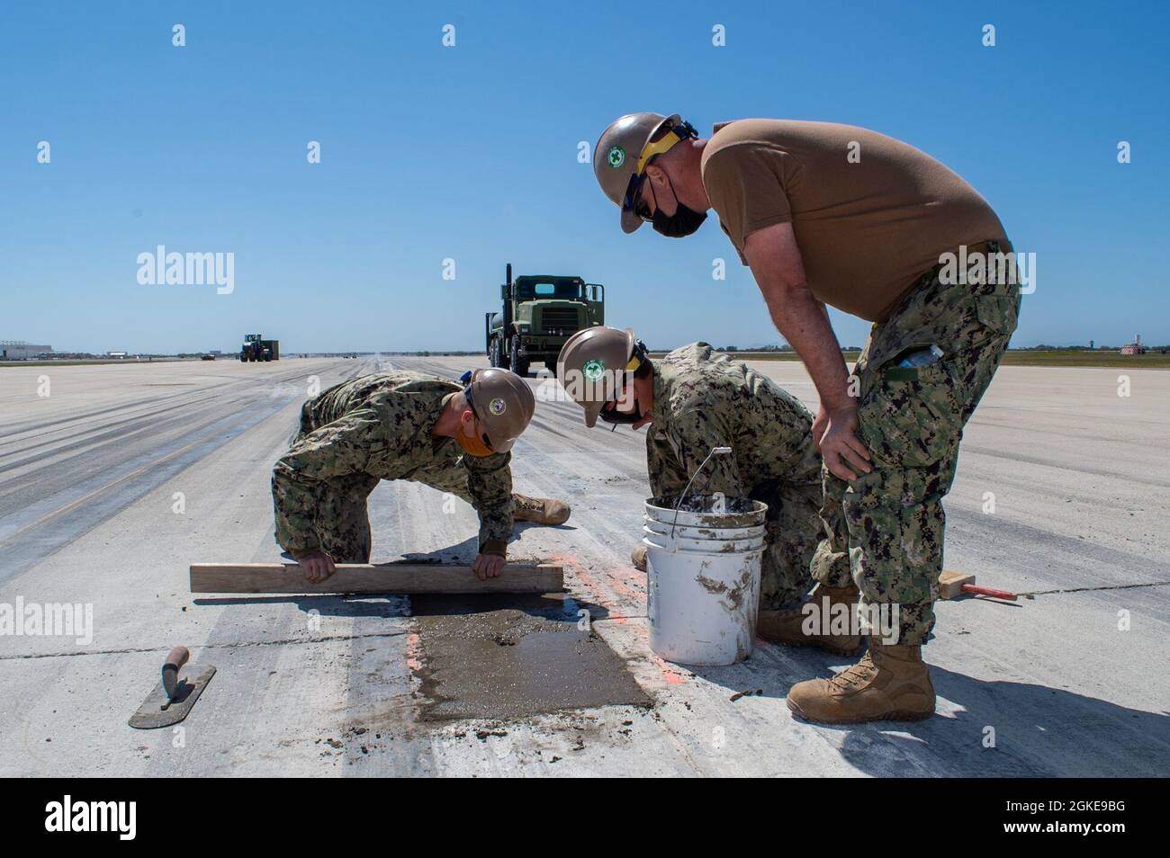 210327-N-PG340-1026 PORT HUENEME (Californie) (27 mars 2021) Steelworker 2nd Class Douglas Dooley (à gauche), 1st Class Raymond Fenton (au centre), et Construction Electricien Constructionman Alexander Hackie, affecté au NMCB (Naval Mobile Construction Battalion) 5, ont réparé le constructeur de piste de la base navale Ventura County, point Mugu (Californie). Les Seabees avec NMCB-5 ont réparé 24 salopettes chronocritiques à travers l'axe de la piste. Ces réparations permettent aux opérations aériennes de point Mugu de retrouver leur pleine capacité d'exploitation sur la ligne de vol de 1,100 pieds Banque D'Images