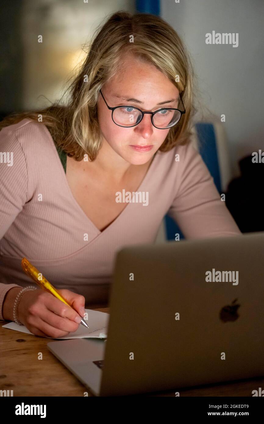 Une jeune femme est assise devant un ordinateur portable et travaille Banque D'Images