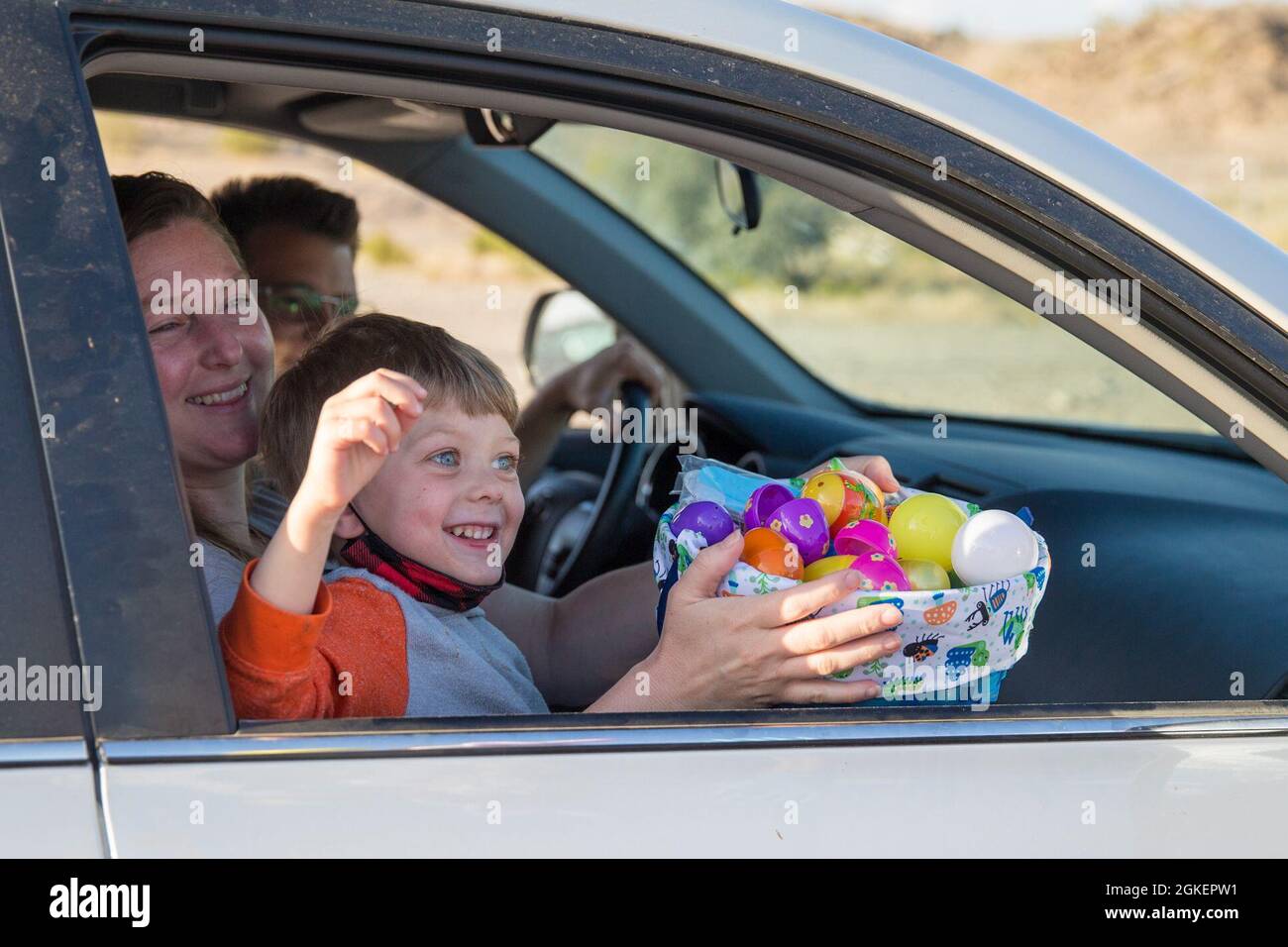 Un enfant récolte des œufs pendant l'Eggstravaganza de Pâques sur la base aérienne du corps des Marines Yuma, le 1er avril 2021. L'événement de passage en voiture a permis aux enfants militaires et à leurs familles de participer à l'excitation de la collecte d'œufs, de jouets et de bonbons. Banque D'Images