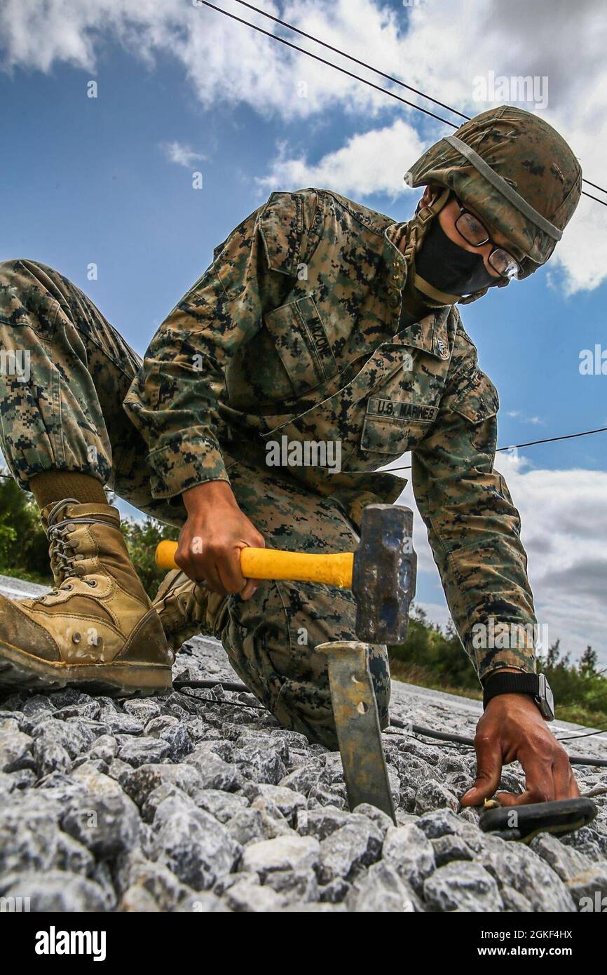 Sergent du corps des Marines des États-Unis Raphael Mazone, administrateur de systèmes de données avec 3d Supply BN, lance un pieu sur le terrain pour fixer une ligne directrice soutenant un système radio multi-canal MRC-142D lors d'un exercice de formation sur le terrain à Camp Hansen, Okinawa, Japon, le 6 avril 2021. La mission de 3d Supply BN est de fournir un support logistique réactif et de qualité à III MEF et à d'autres forces maritimes, conjointes, combinées et fédérales, comme indiqué par des moyens expéditionnaires, des forward basing et un approvisionnement mondial. le mlg 3d, basé à Okinawa, au Japon, est une unité de combat déployée en avant qui sert de compr du MEF III Banque D'Images