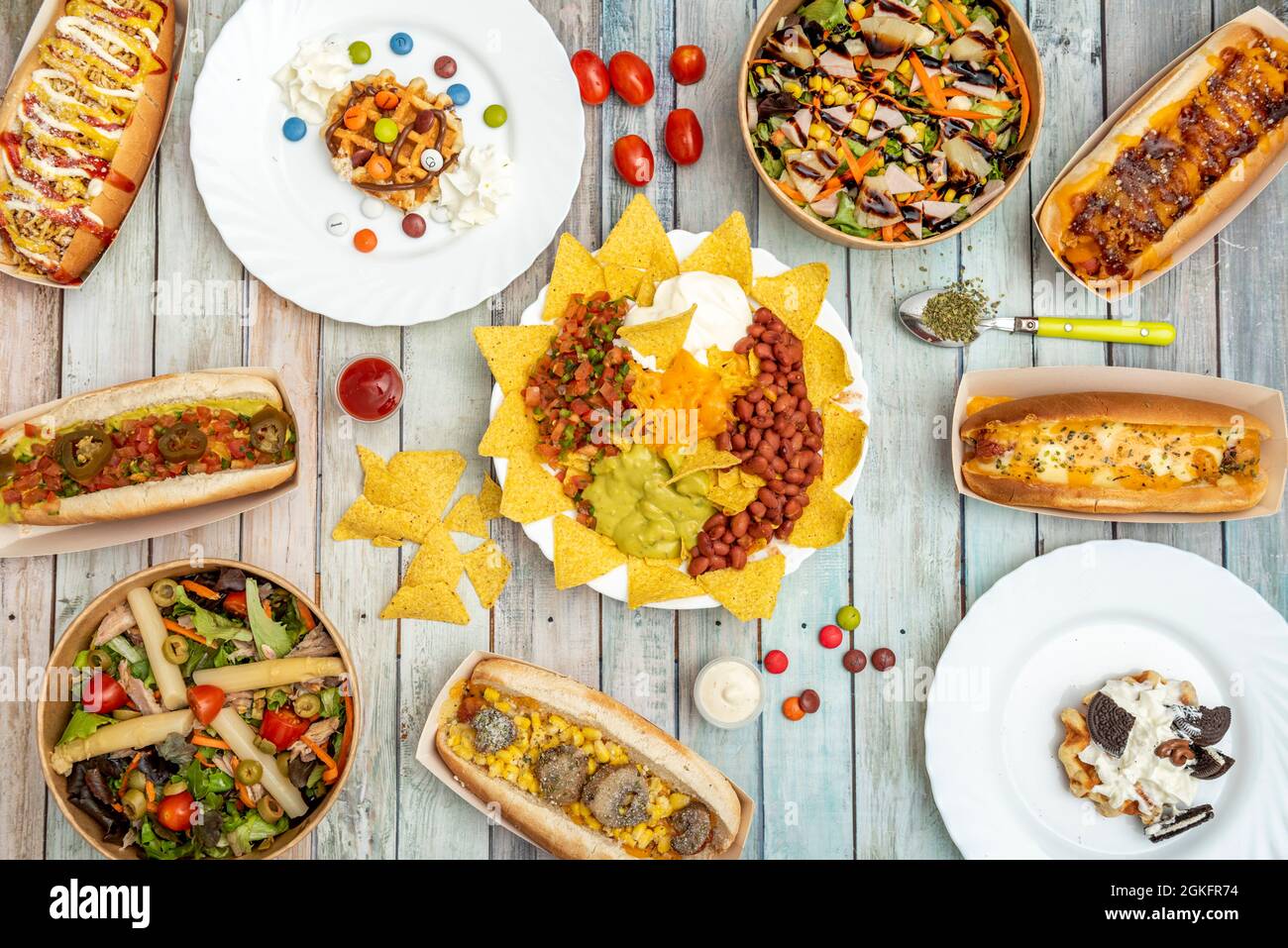 Foto top View de platos mexicanos, perritos calientes, ensaladas en Bowl de servicio a domicilio y postes con lacasitos sobre fondo de madera Banque D'Images
