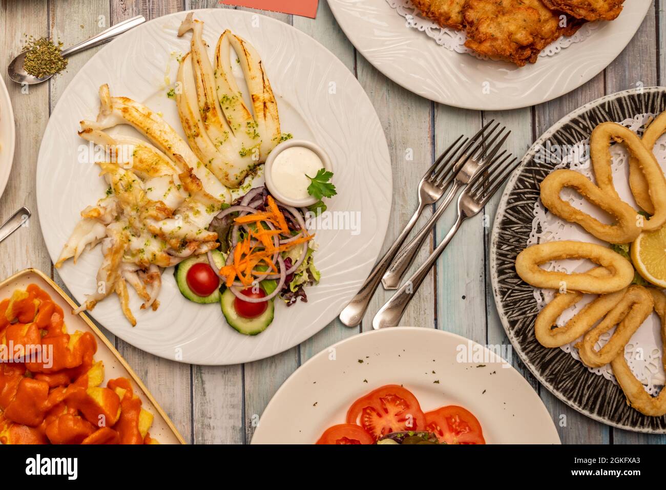 Plats typiques de restaurant à tapas, seiches grillées, calmar romain, œufs brouillés au jambon, croquettes de morue, patatas bravas. Banque D'Images
