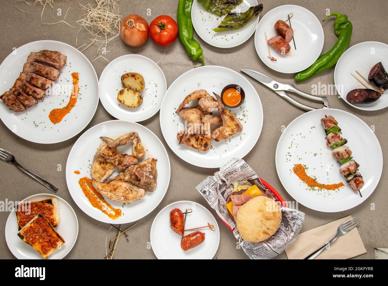 Ensemble de plats grillés sur une grille au charbon de bois sur une table grise. Rôti de pomme de terre, rôti de chorizo, brochette de poulet, côtes de porc, hamburger de bœuf. Banque D'Images