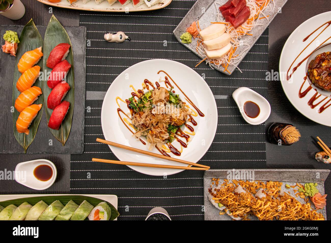 Vue de dessus des plats japonais. Sushi nigiri au saumon norvégien et au thon rouge, octopus takoyaki, sushi sashimi au poisson de bream, uramaki california rol Banque D'Images