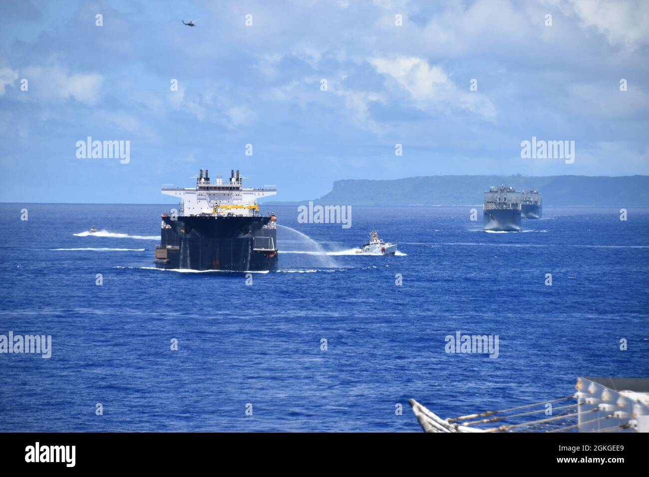 Lors de la vaporisation dans une formation près de Guam, USNS Montford point utilise son tuyau, une réponse préplanifiée, qu'il pourrait utiliser pendant les opérations de convoi. Sur la photo, de gauche à droite, on trouve un bateau Mark VI du Groupe côtier 1, USNS Montford point (T-ESD 1), un navire de la Garde côtière américaine Myrtle Hazard (WPC-1139), un USNS Red Cloud (T-AKR 313), USNS Watkins (T-AKR 315) et, dans les airs, un MH-60R du Escadron de combat en mer 25. Banque D'Images