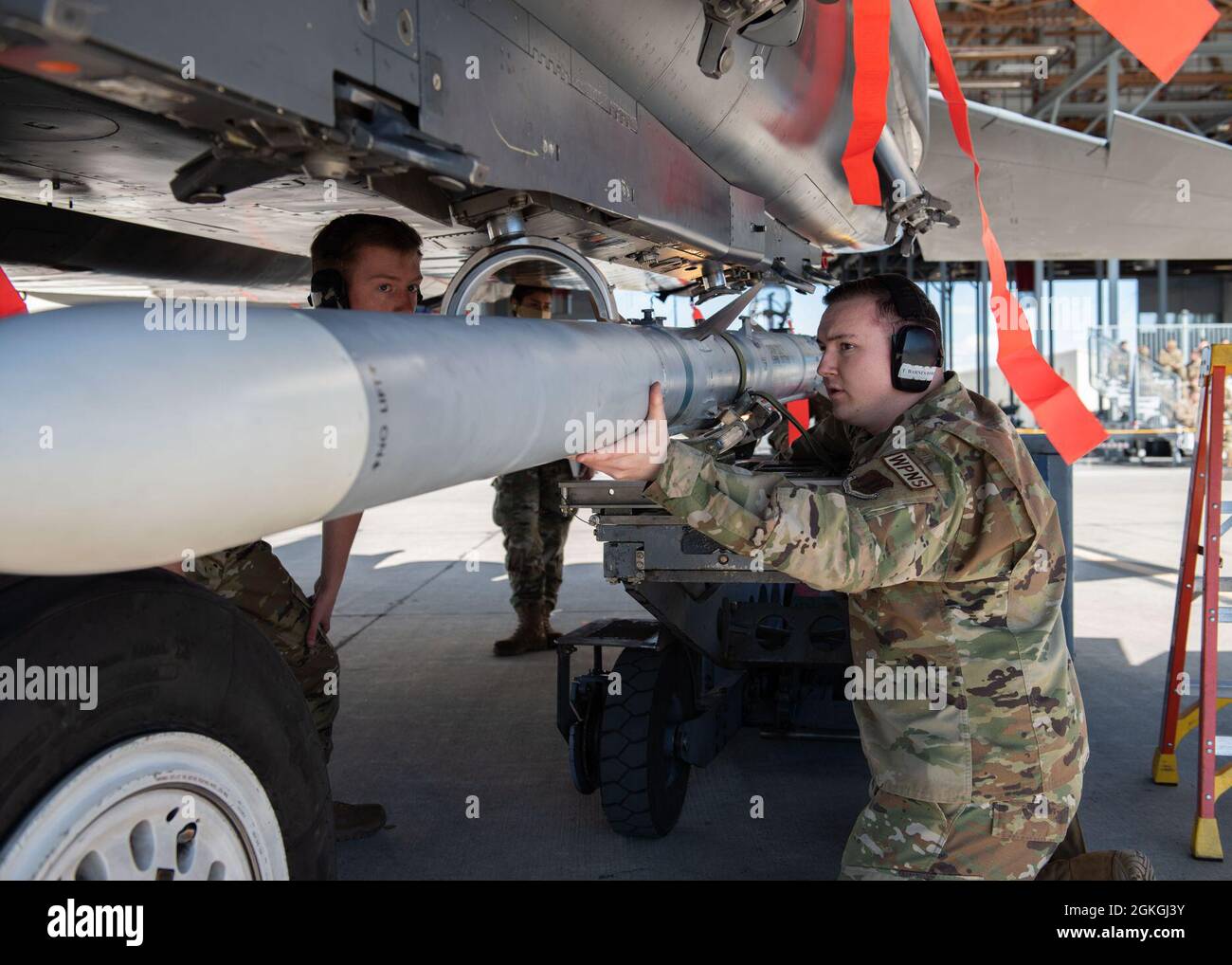 Sergent d'état-major de la Force aérienne des États-Unis Tryton Barnes, membre de l'équipage de chargement du 391e Escadron de chasseurs, aide son équipage de trois hommes à charger un missile Air Intercept dans un F-15E Strike Eagle, le 16 avril 2021, à la base aérienne de Mountain Home, dans l'Idaho. Le concours trimestriel de l'équipage de charge teste la vitesse et les compétences d'un équipage de trois personnes qui charge des munitions dans un avion. Banque D'Images