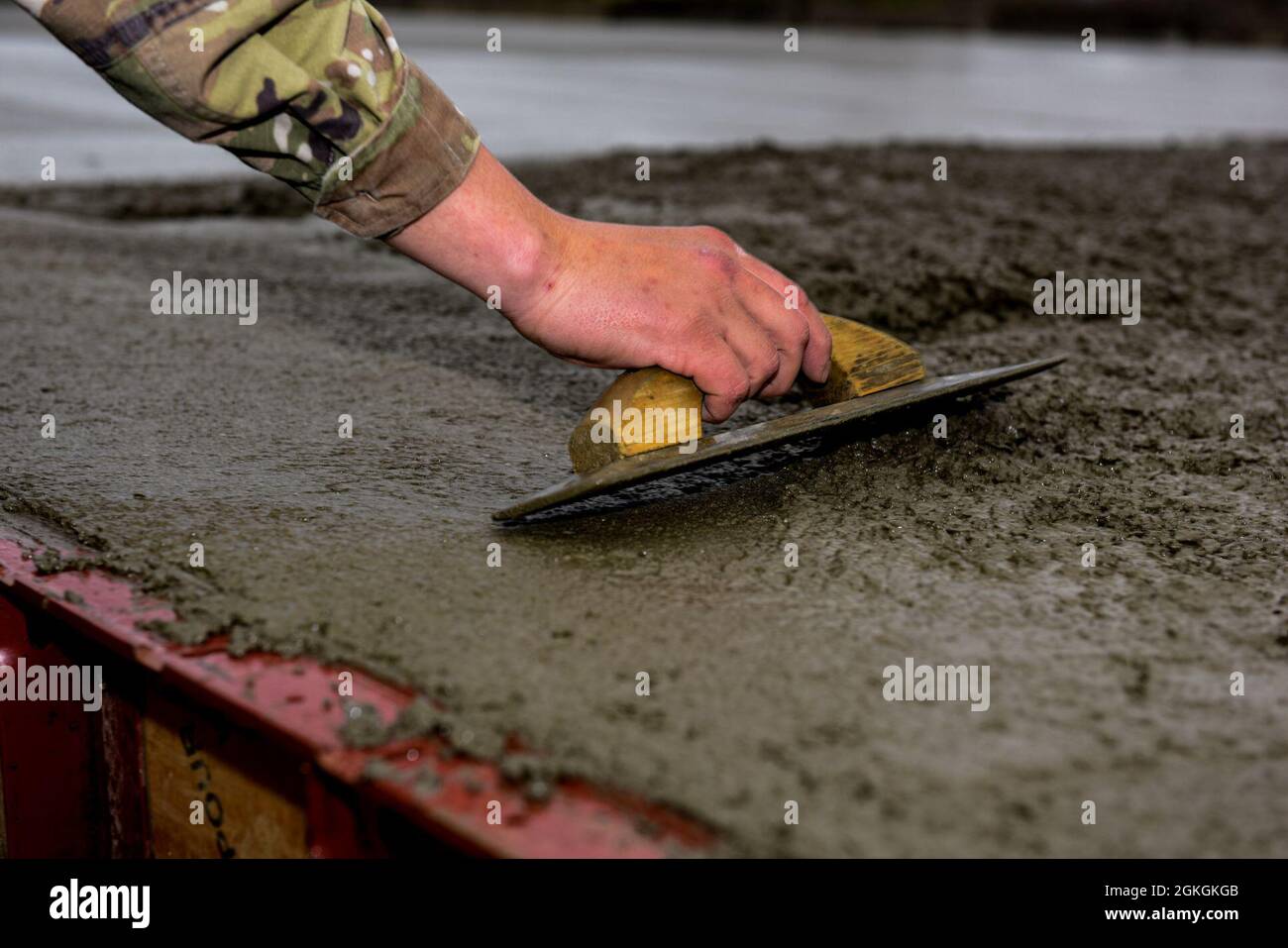 Pennsylvania Air National Guardsman, Capt Matthew Saccone, affecté au 171e Escadron de génie civil de la Escadre de ravitaillement en vol, utilise une truelle manuelle pour la table du dessus du béton, le 16 avril 2021. Crier aide à compacter et à consolider le béton, et commence le processus de lissage et de nivellement (Pennsylvania A Banque D'Images