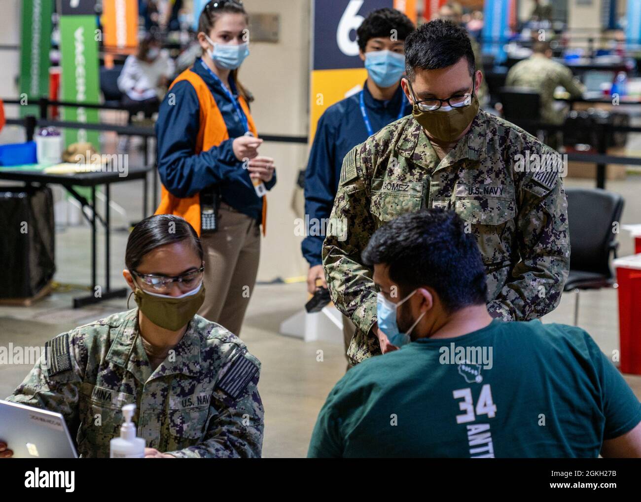 U.S. Navy Hospital Corpsman 3rd Class Emanuel Gomez, à droite, originaire de San Antonio affecté au Naval Medical Center Portsmouth (NMCP), Virginie, traduit pour l'Hospitalman de la Marine américaine Jennifer Mina, à gauche, originaire de Delano, Californie affecté au PNLP au Centre de vaccination communautaire du Hynes Convention Center à Boston, 20 avril 2021. Gomez se porte volontaires pour traduire en espagnol pour aider les marins à communiquer avec les membres de la communauté à leurs postes de vaccination. Des marins de la Marine américaine de partout au pays sont déployés à l'appui des opérations fédérales d'intervention contre les vaccins du ministère de la Défense. Banque D'Images