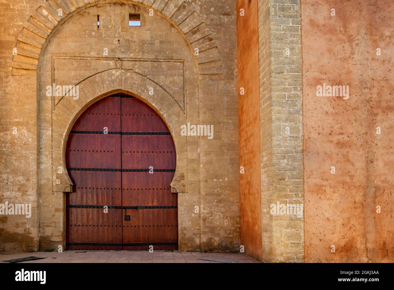 Porte arabe Bab laalou dans le mur de la médina de Rabat au Maroc. Bois verni rougeâtre et pierre plaquées dans des tons ocre Banque D'Images